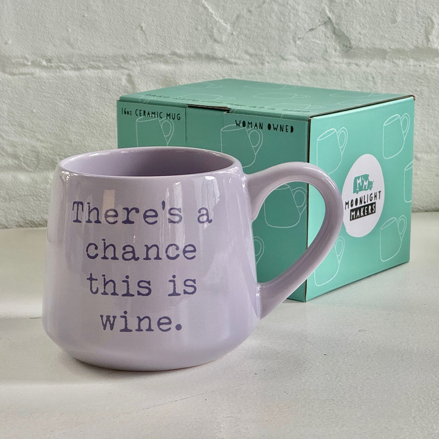 a purple coffee mug sitting next to a box of wine