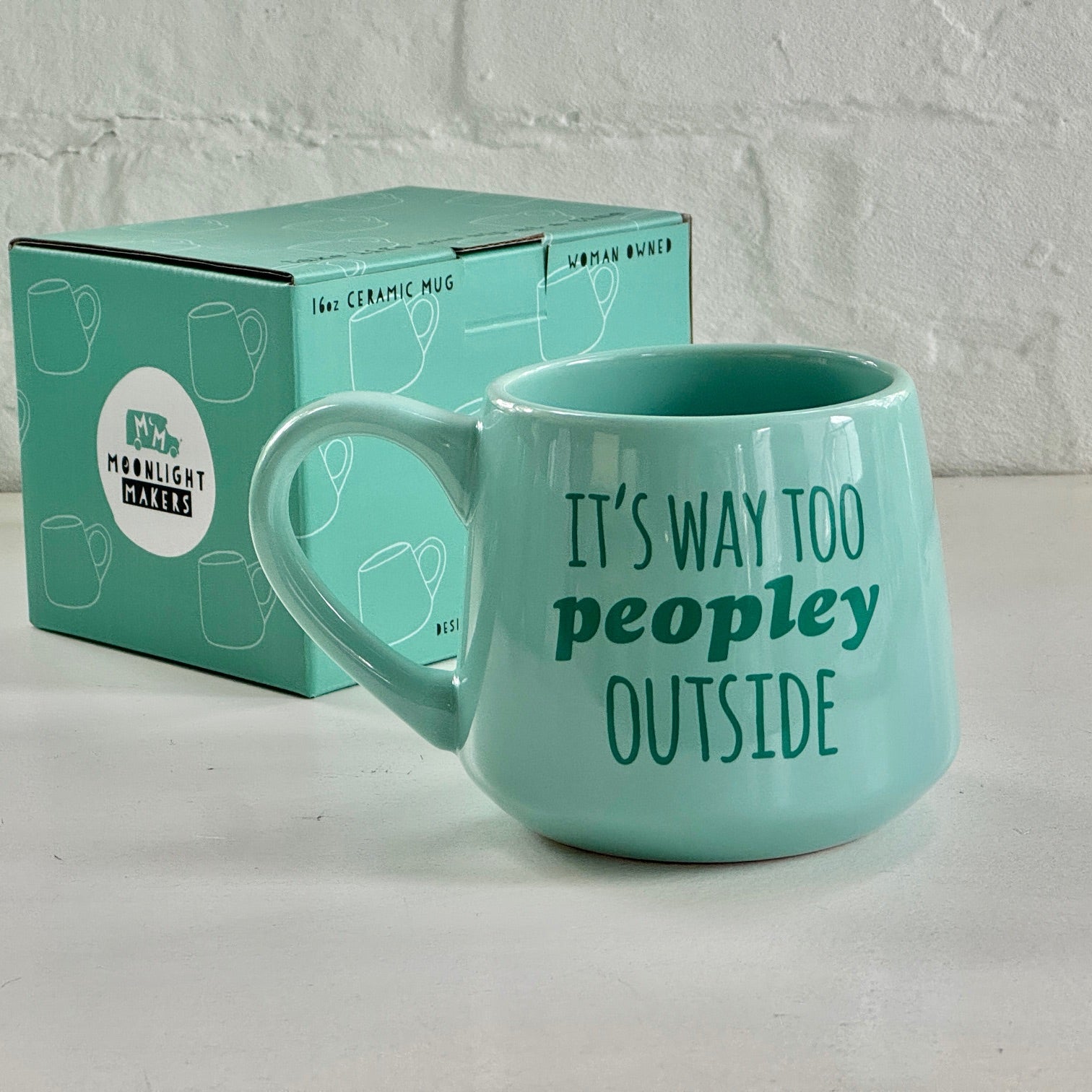 a green coffee mug sitting next to a box