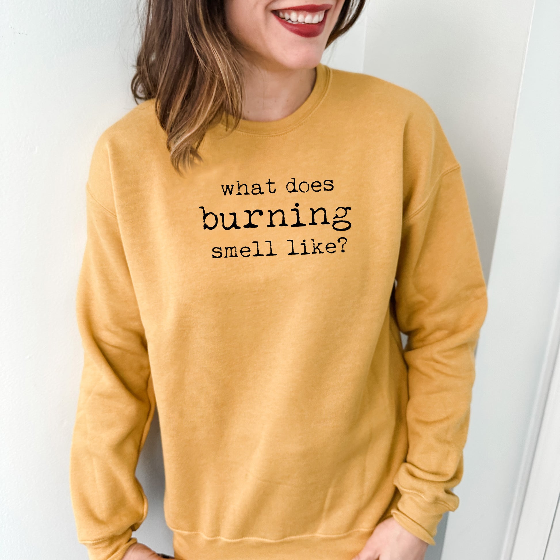 a woman wearing a sweatshirt that says what does burning smell like?