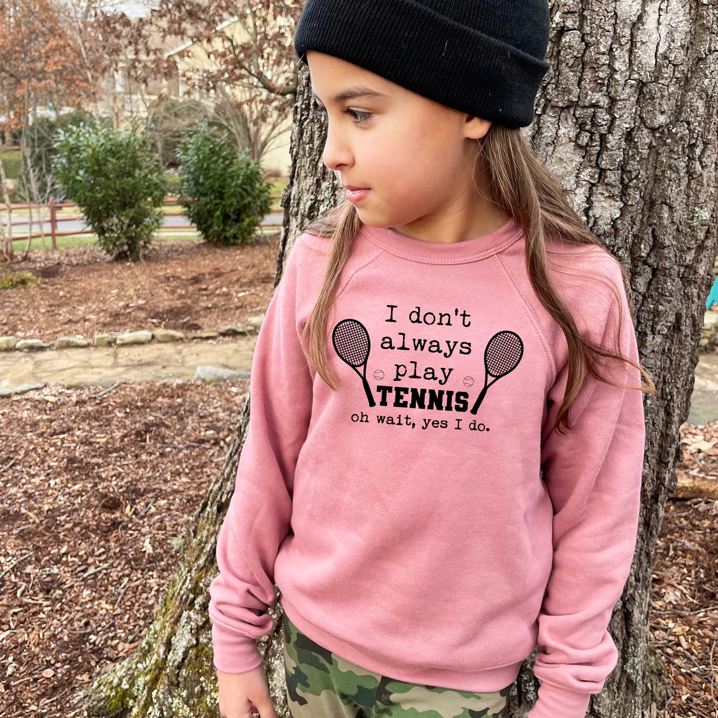 a little girl standing next to a tree