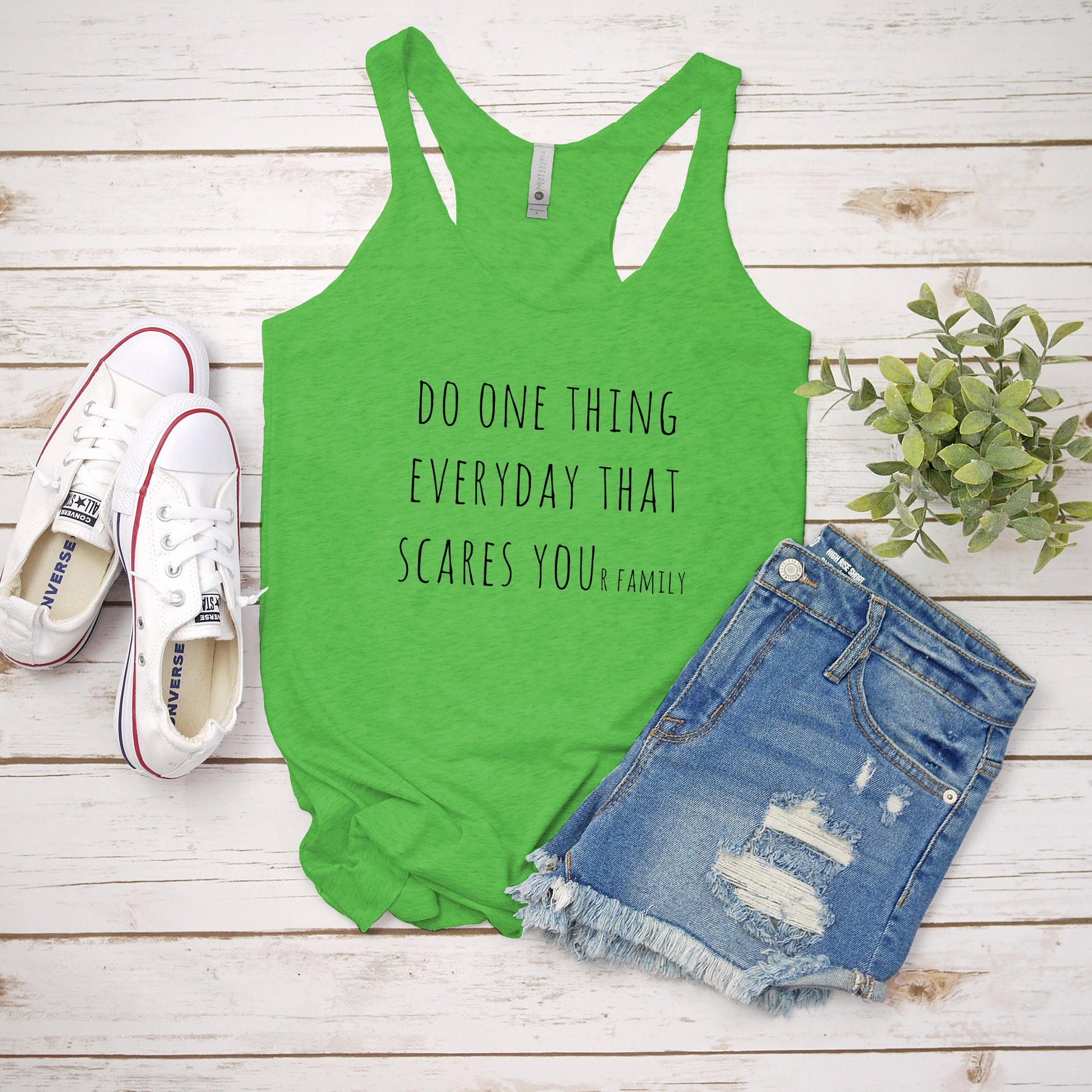 a green tank top that says do one thing everyday that scare you