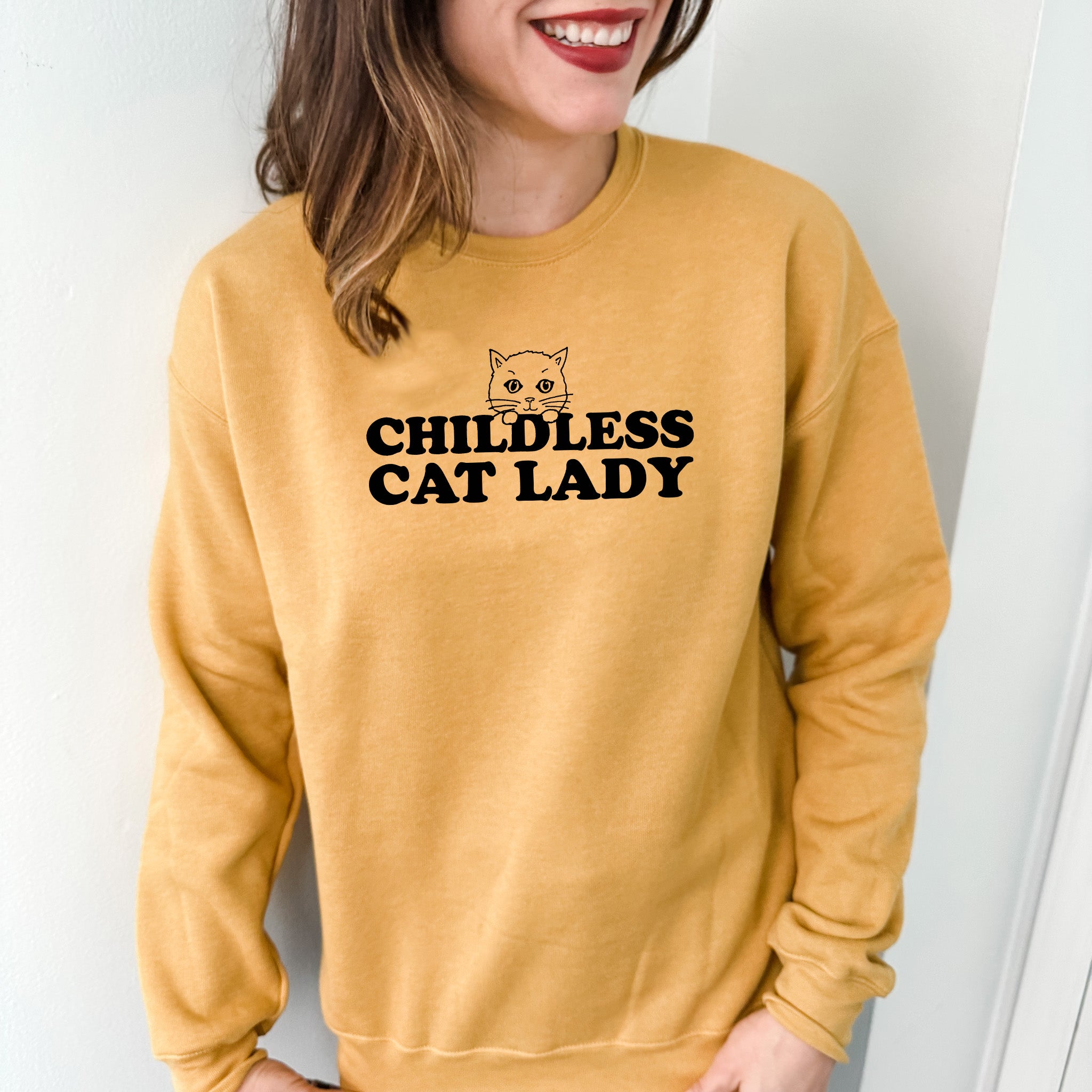a woman wearing a yellow sweatshirt with a cat on it