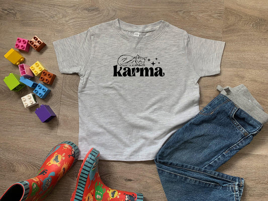 a t - shirt that says karma next to a pair of jeans
