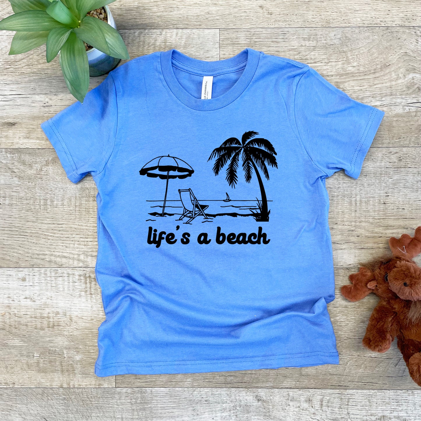 a blue t - shirt that says life's a beach next to a teddy