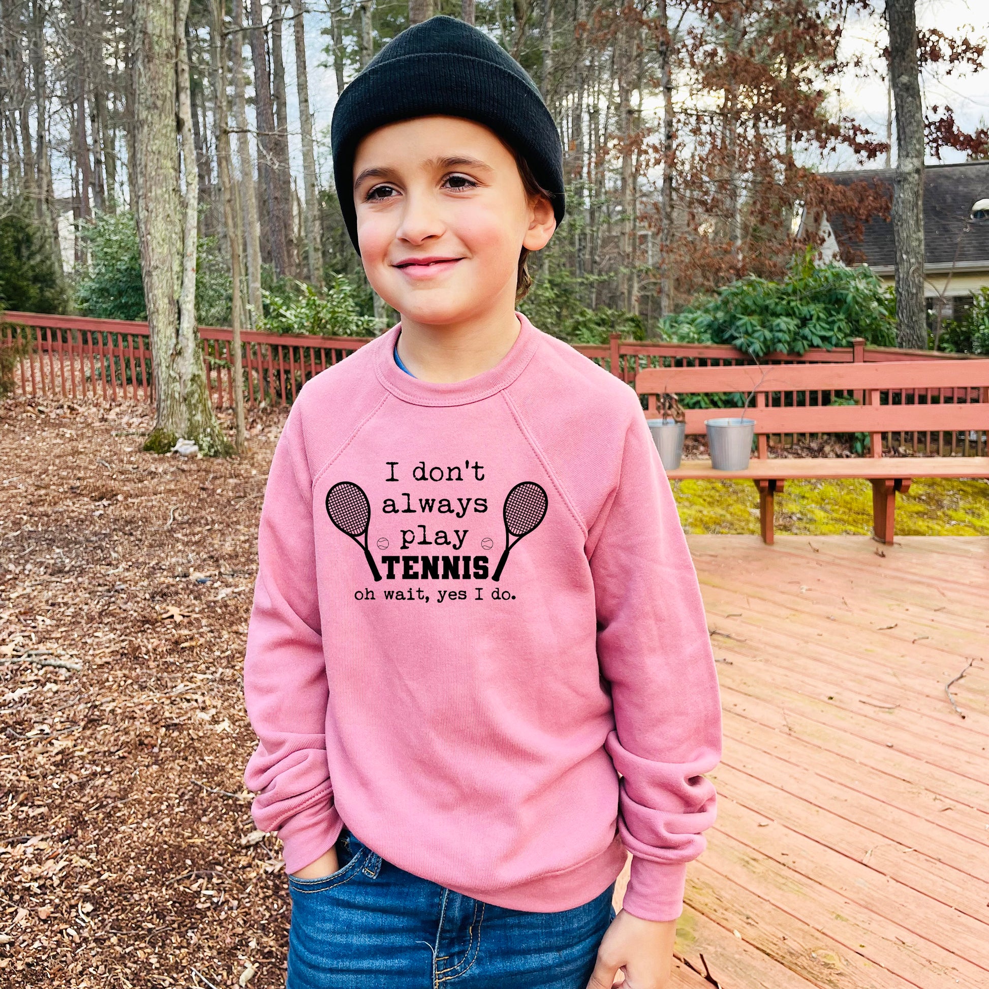 a young boy wearing a pink sweatshirt and a black hat