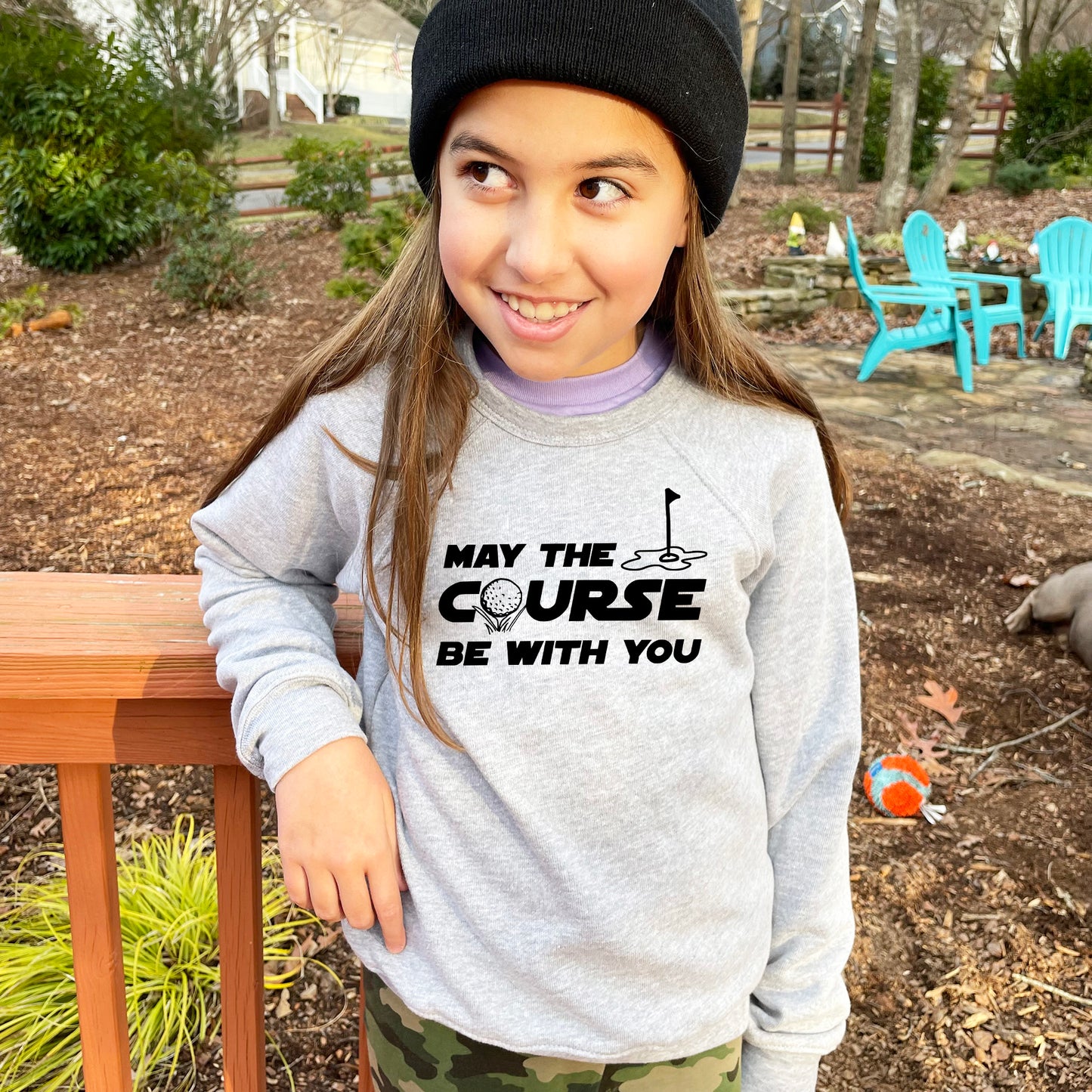 a young girl wearing a gray sweatshirt and a black hat