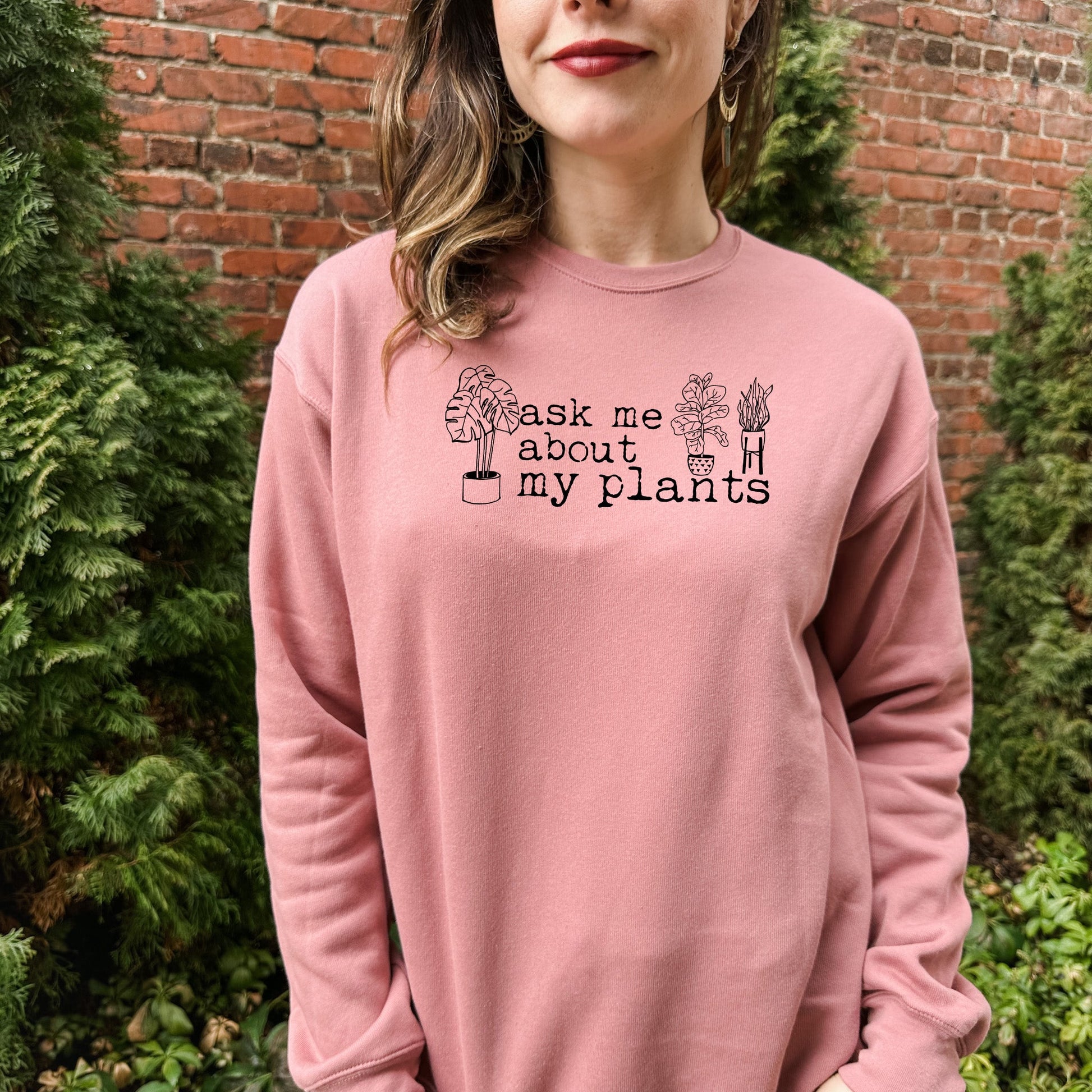 a woman wearing a pink sweatshirt that says ask me about my plants