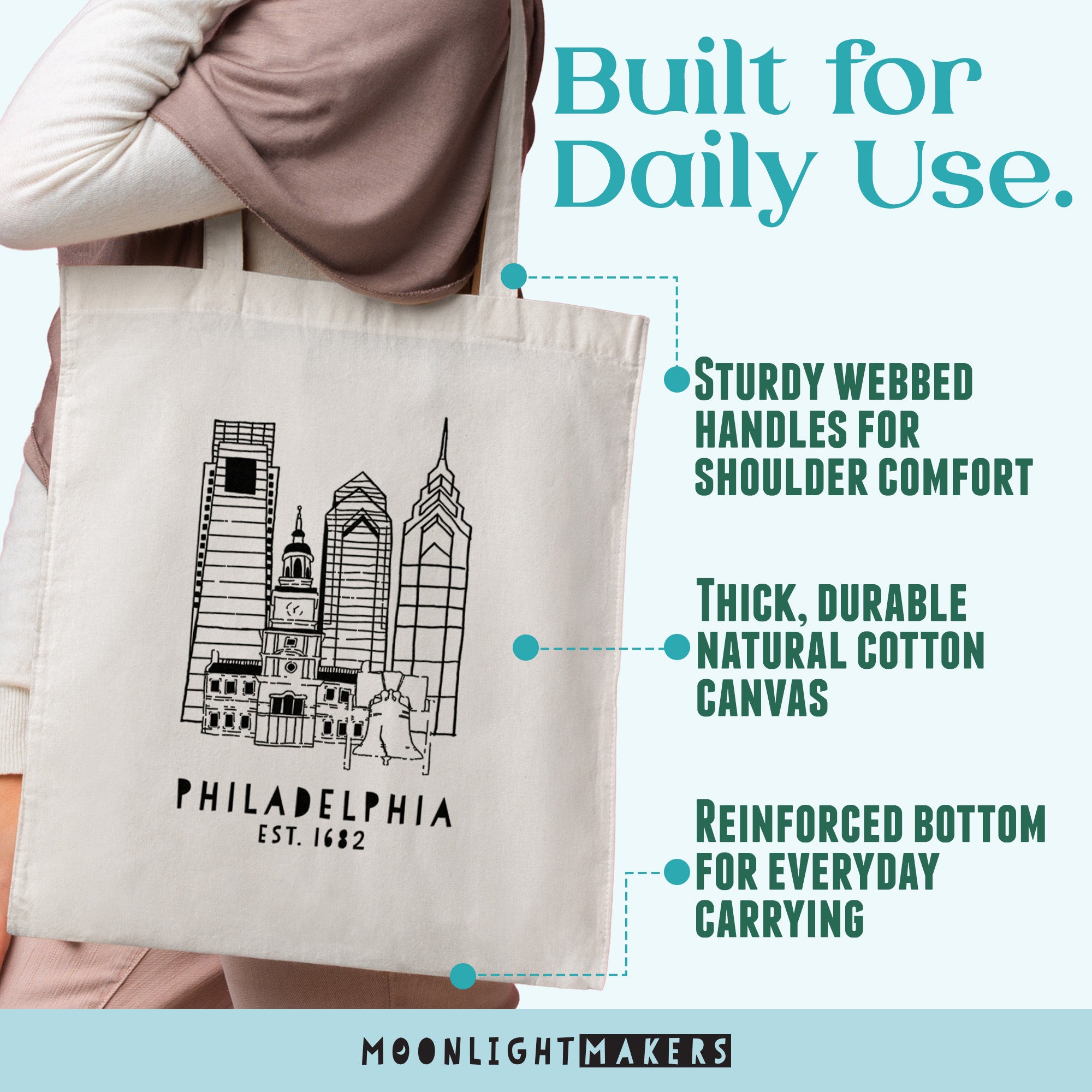 a person holding a Philadelphia tote bag with a cityscape illustration on it.
