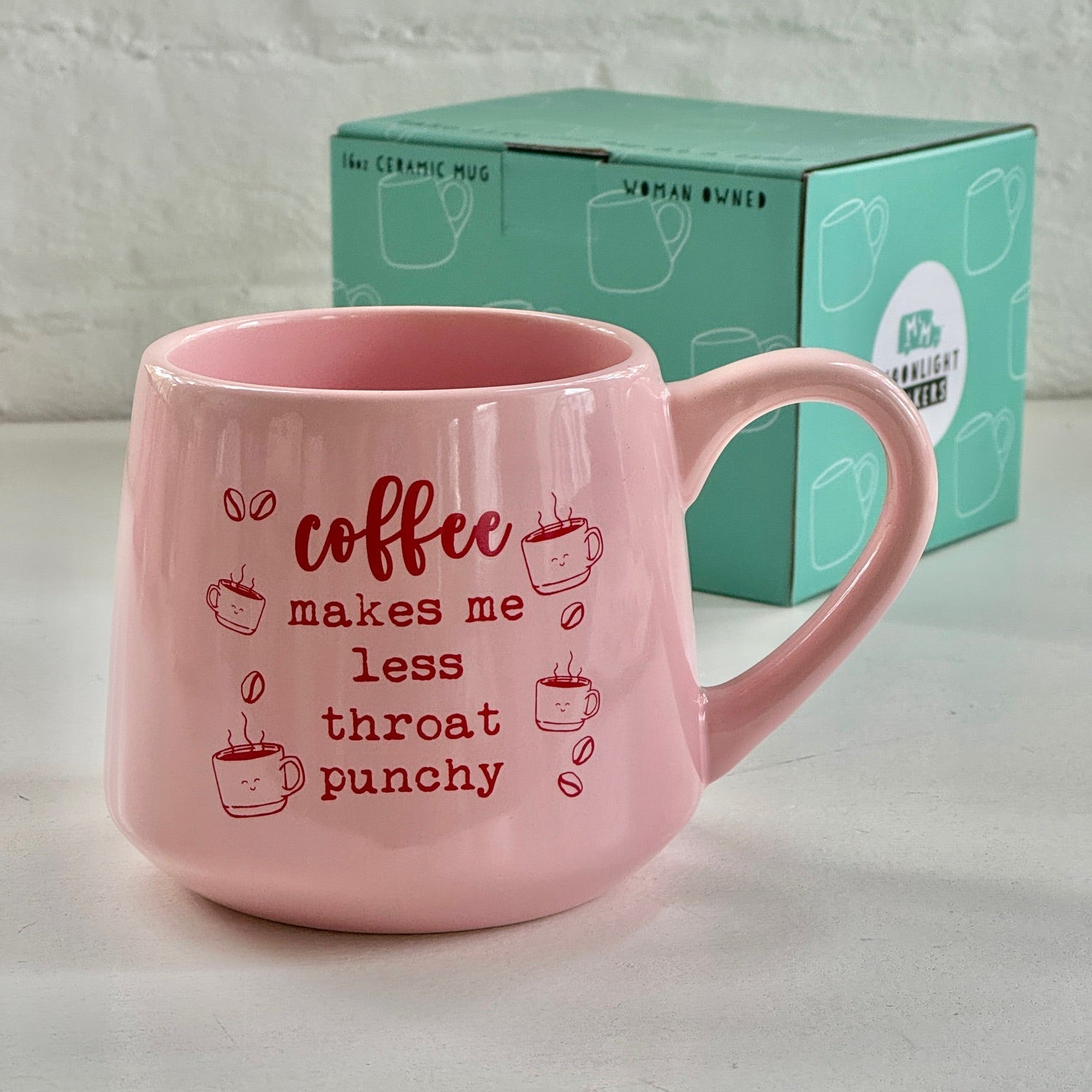 a pink coffee mug sitting next to a box of coffee