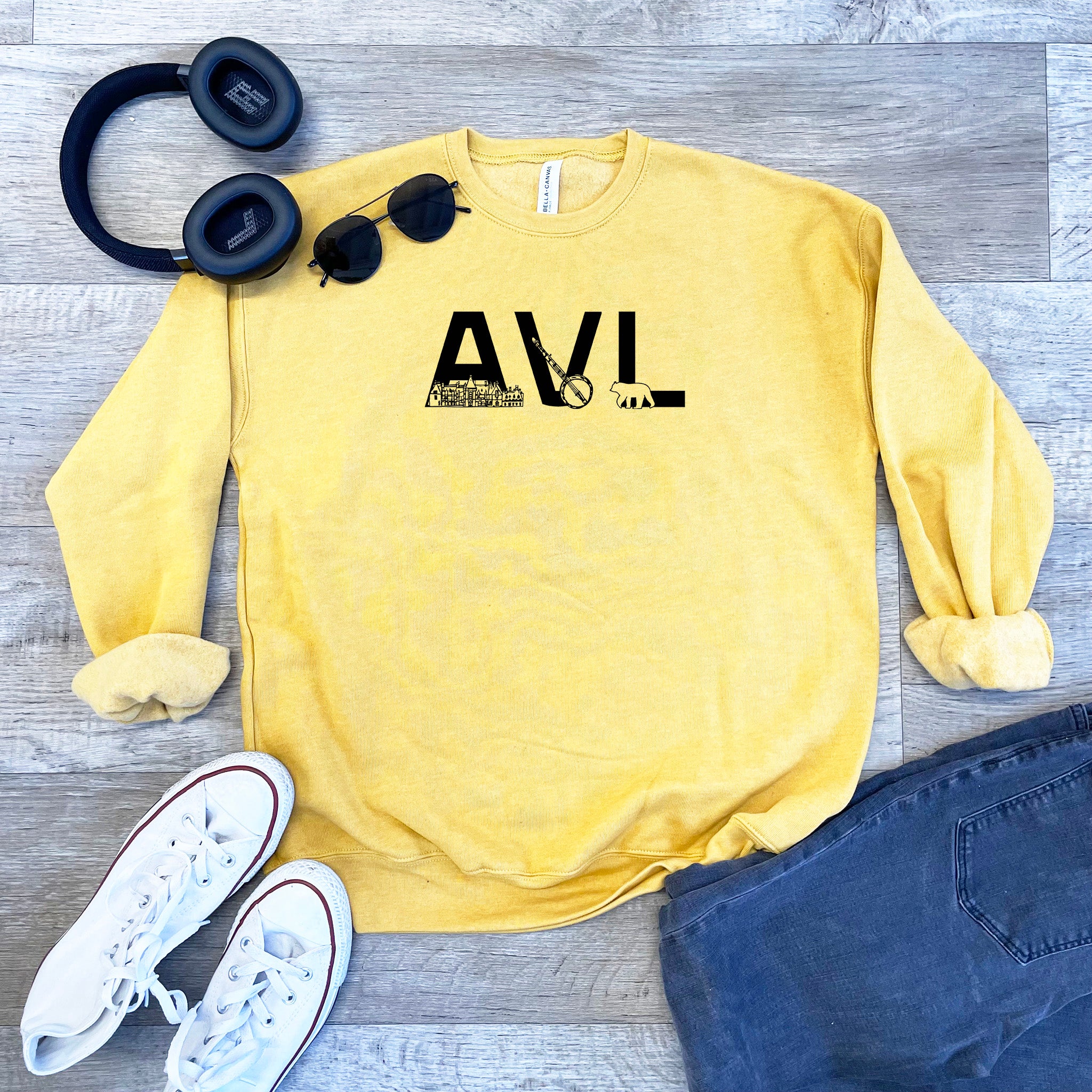 a sweatshirt, headphones, and pair of jeans on a wooden floor