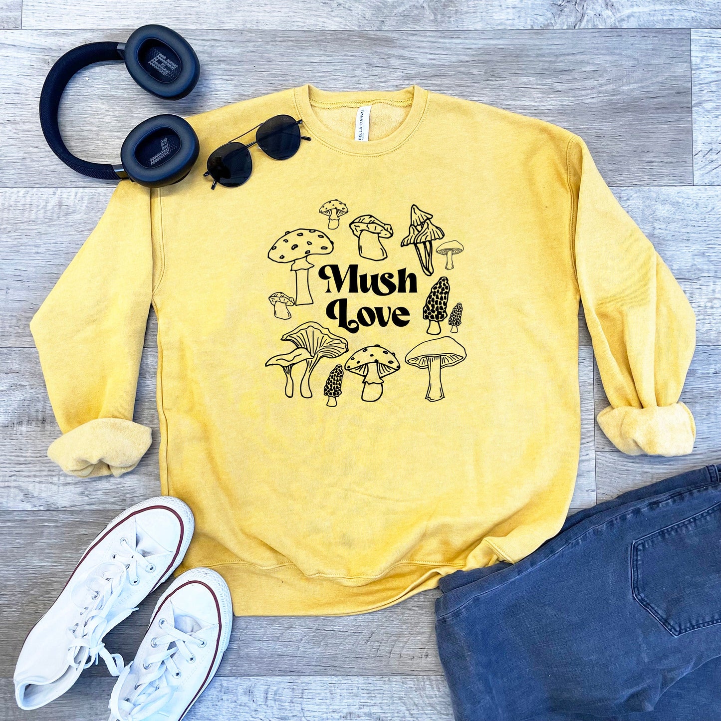 a yellow sweatshirt with mushrooms on it next to a pair of headphones