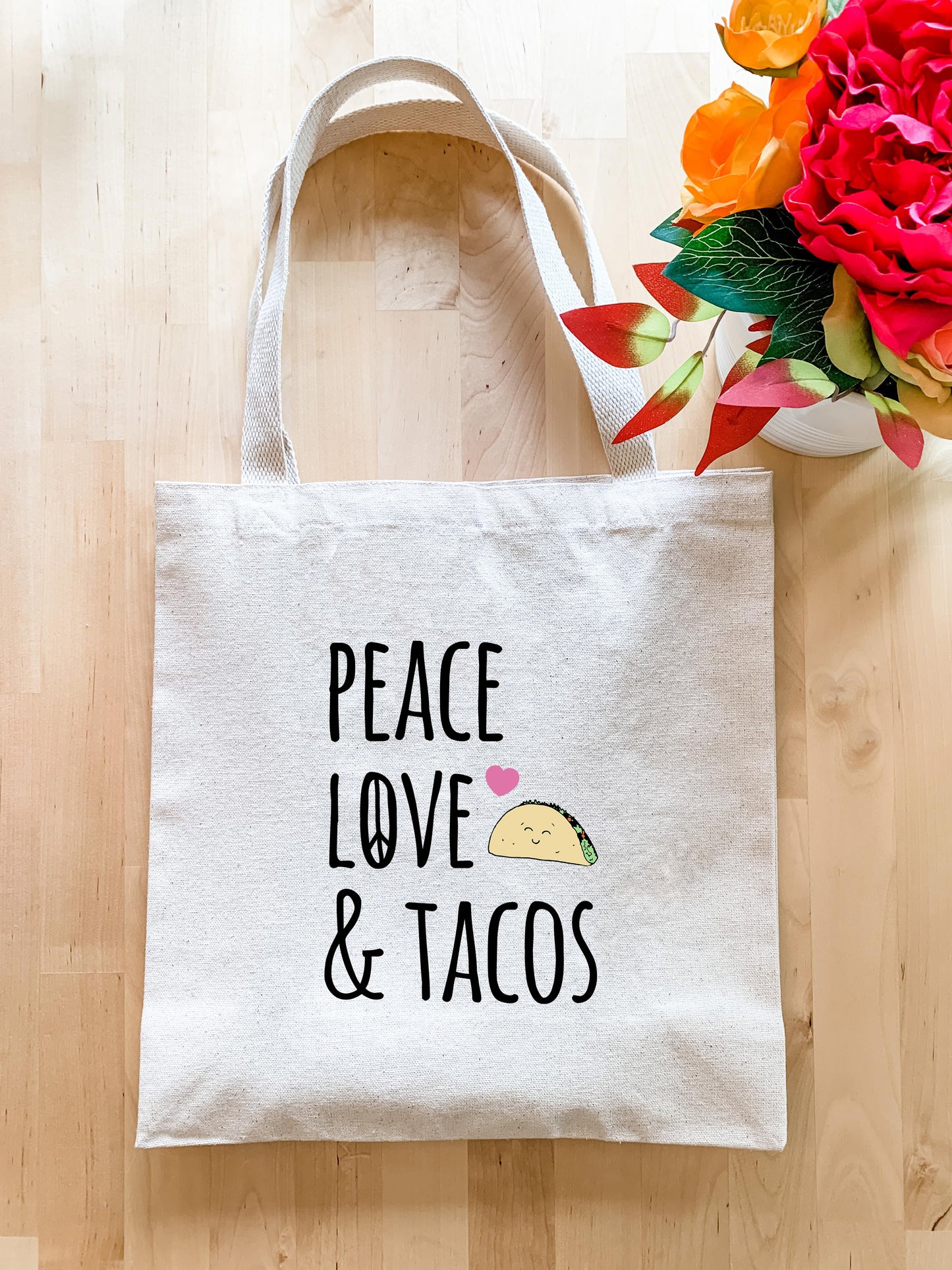 a tote bag with a taco on it next to a vase of flowers