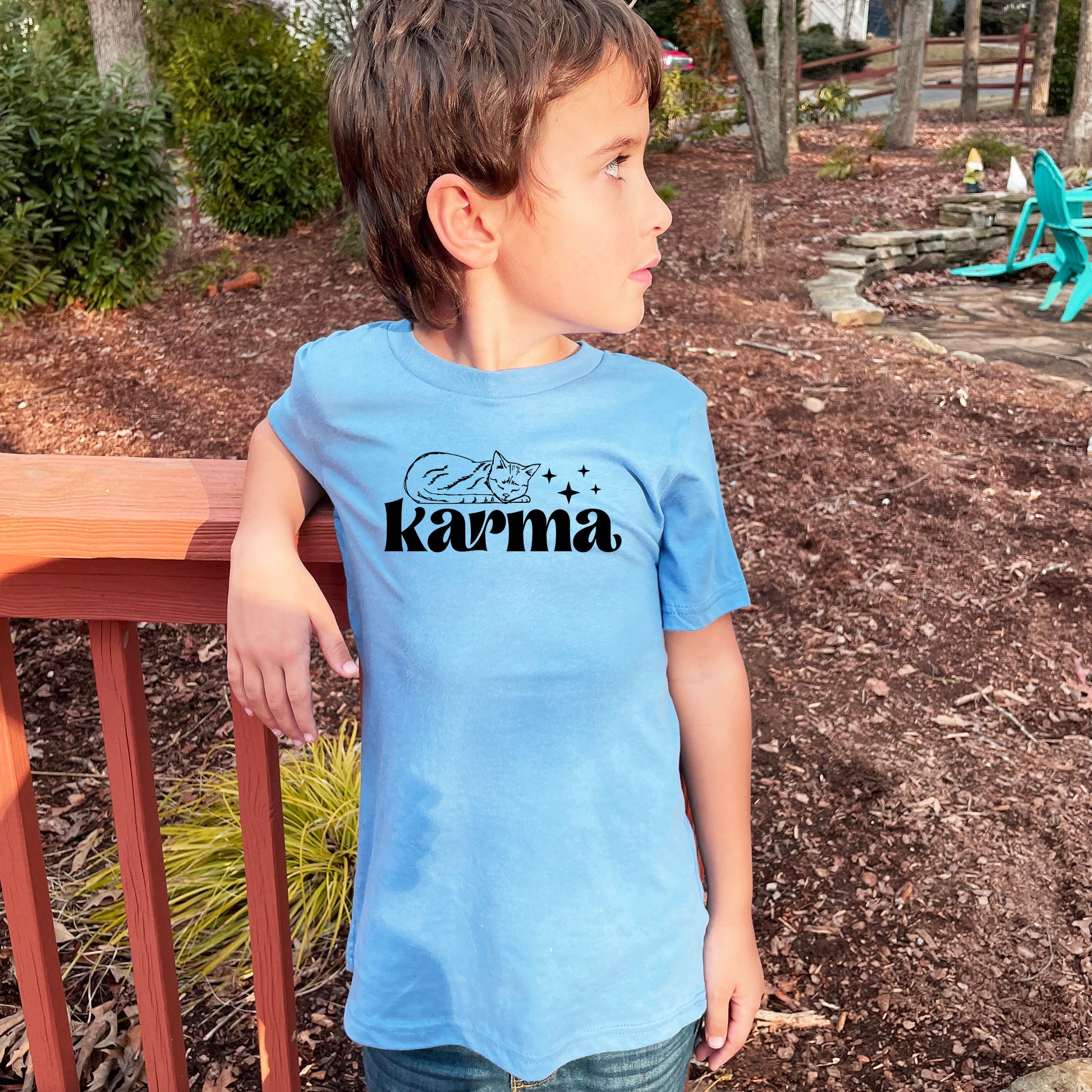 a young boy wearing a blue shirt with the word karma printed on it
