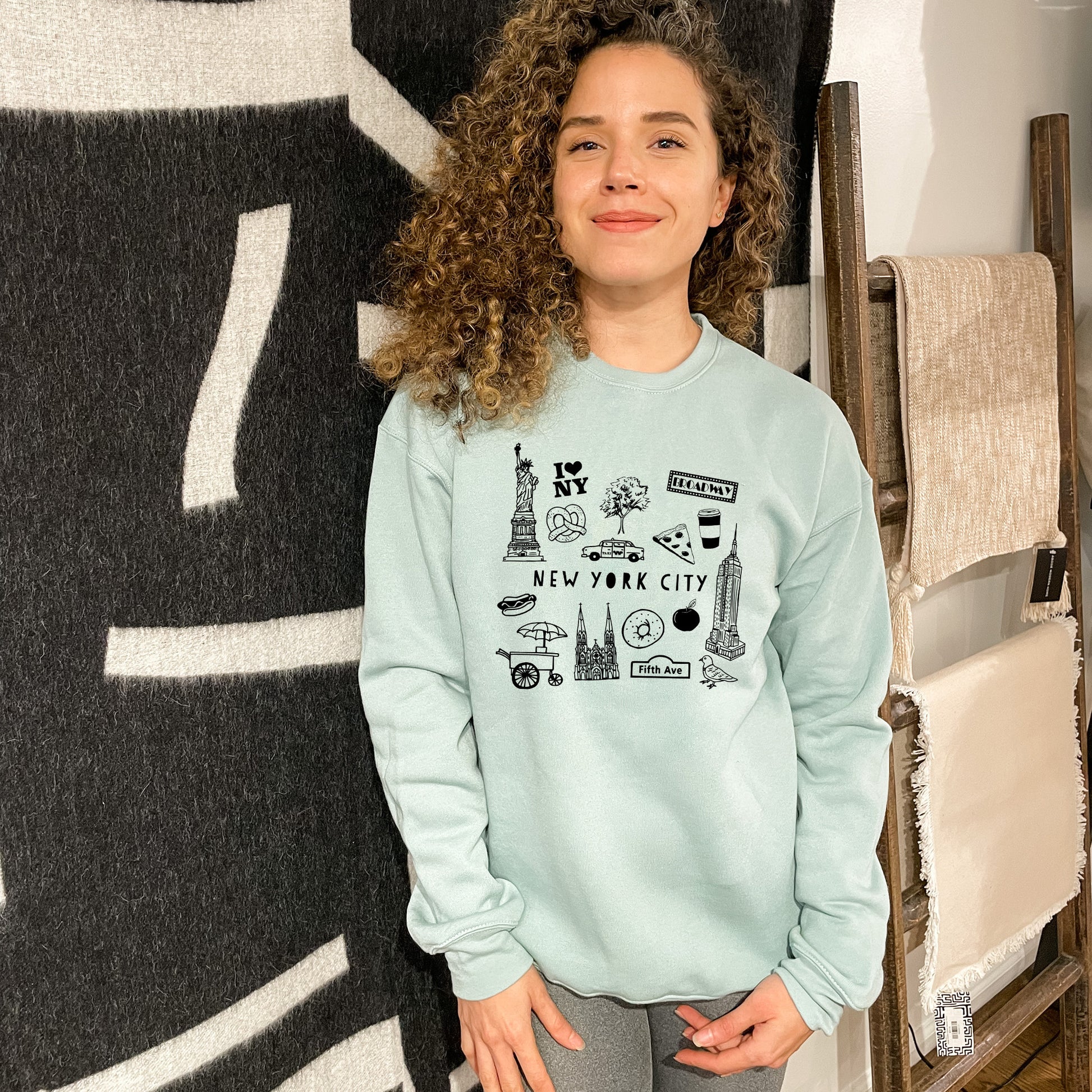 a woman standing in front of a wall wearing a sweatshirt