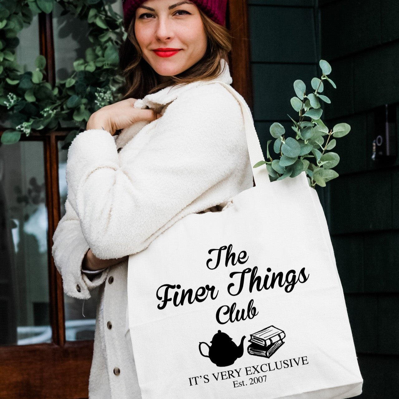 a woman carrying a bag that says the finer things club