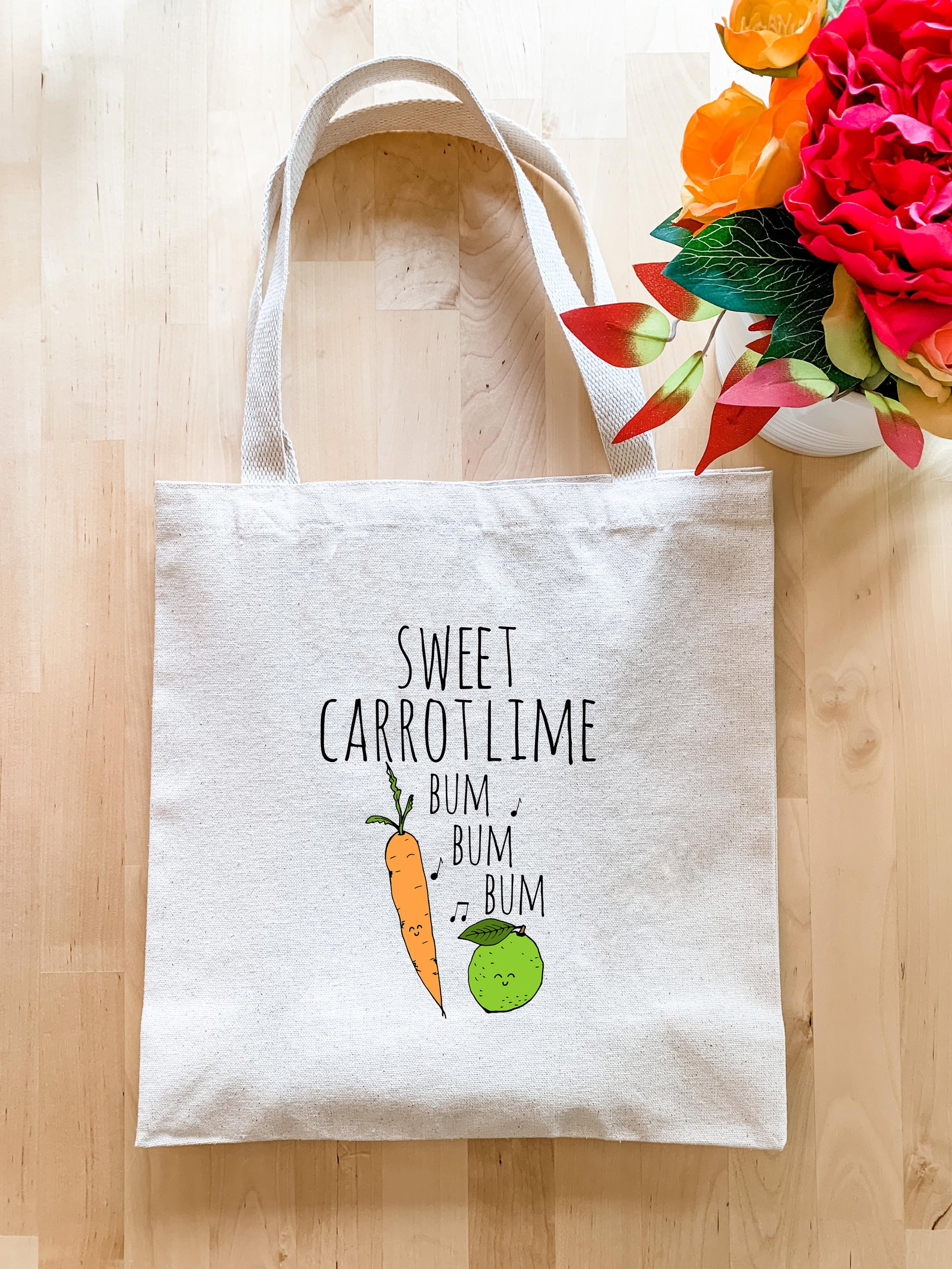 a white bag with a carrot on it next to a vase of flowers