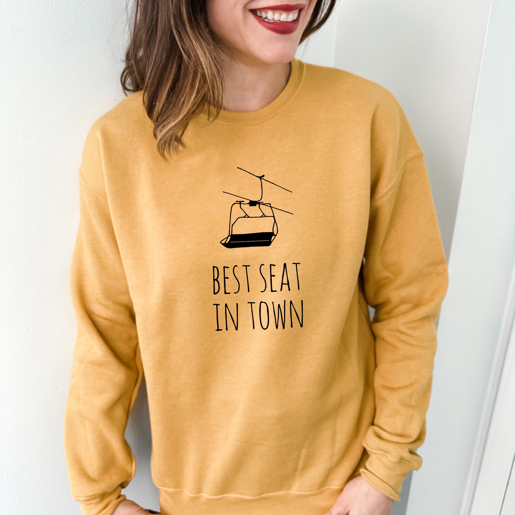 a woman wearing a yellow sweatshirt that says best seat in town