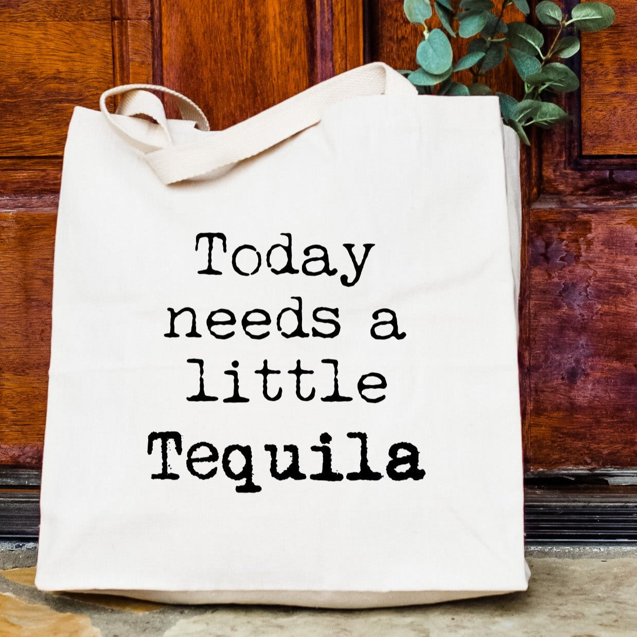 a white tote bag sitting on top of a wooden door