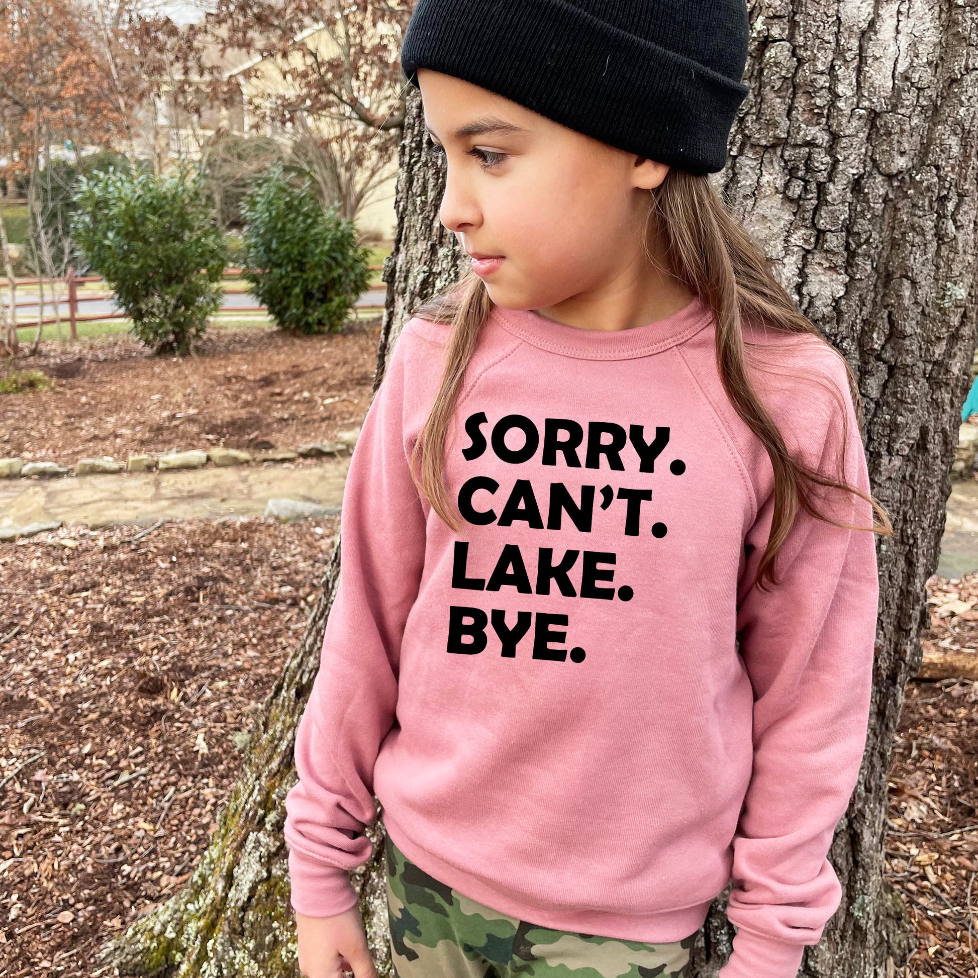 a little girl standing next to a tree