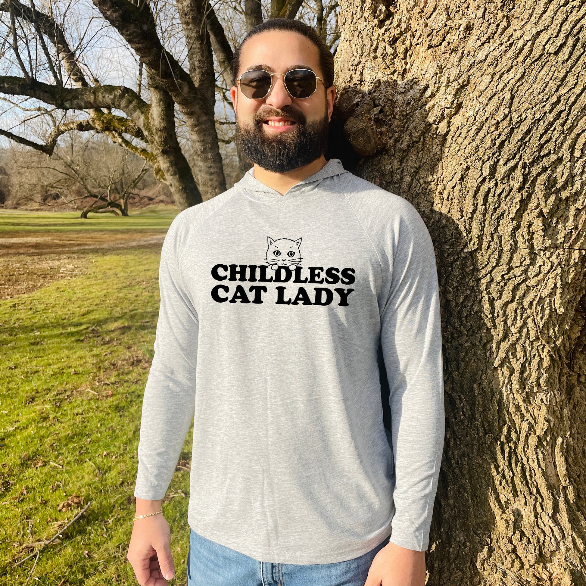 a man standing next to a tree wearing a hoodie