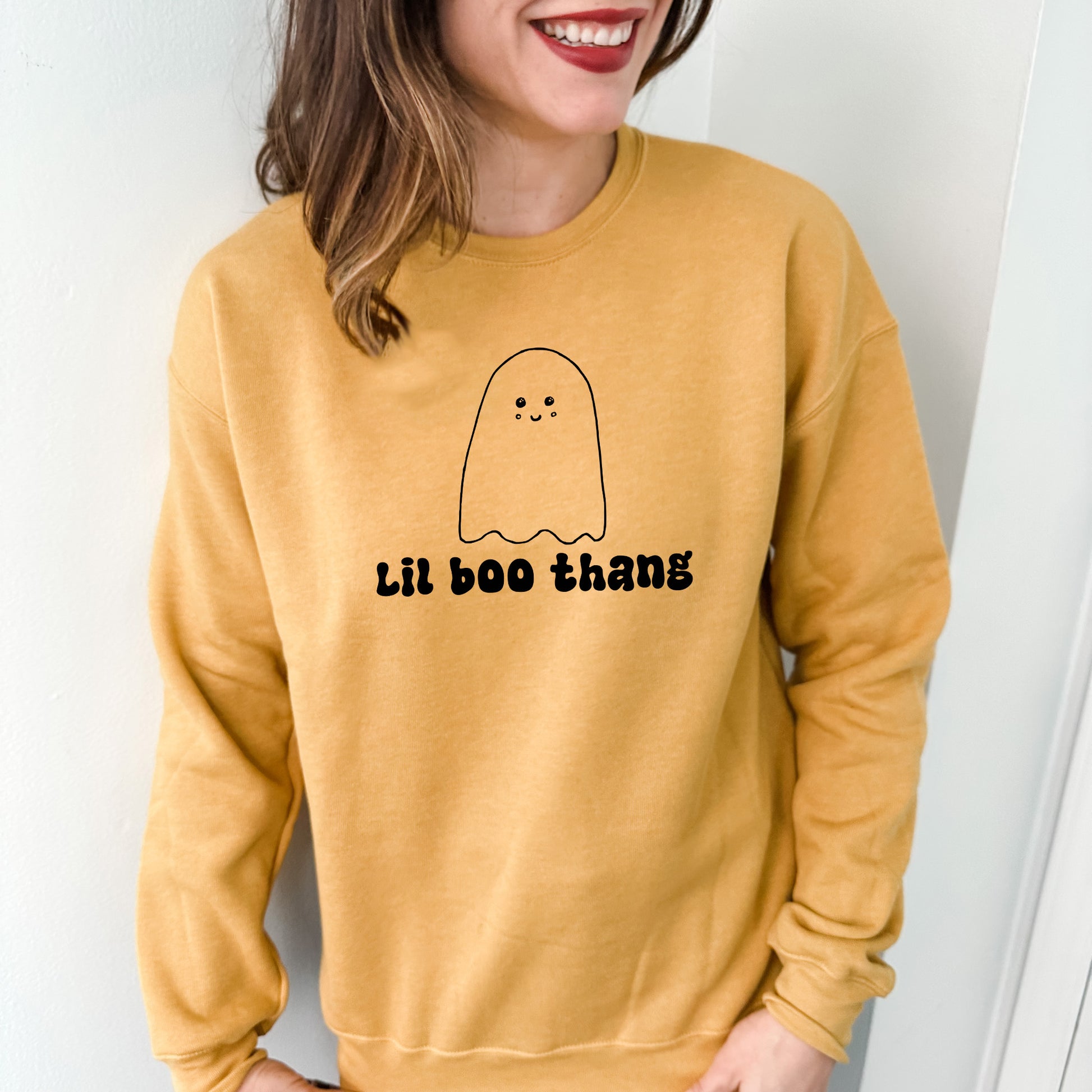 a woman wearing a yellow sweatshirt with a ghost drawn on it