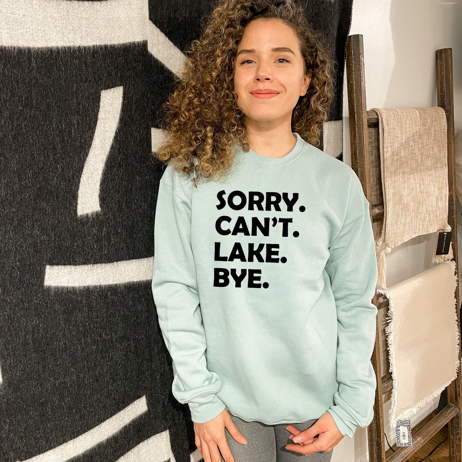 a woman standing in front of a wall wearing a sweatshirt that says sorry, can