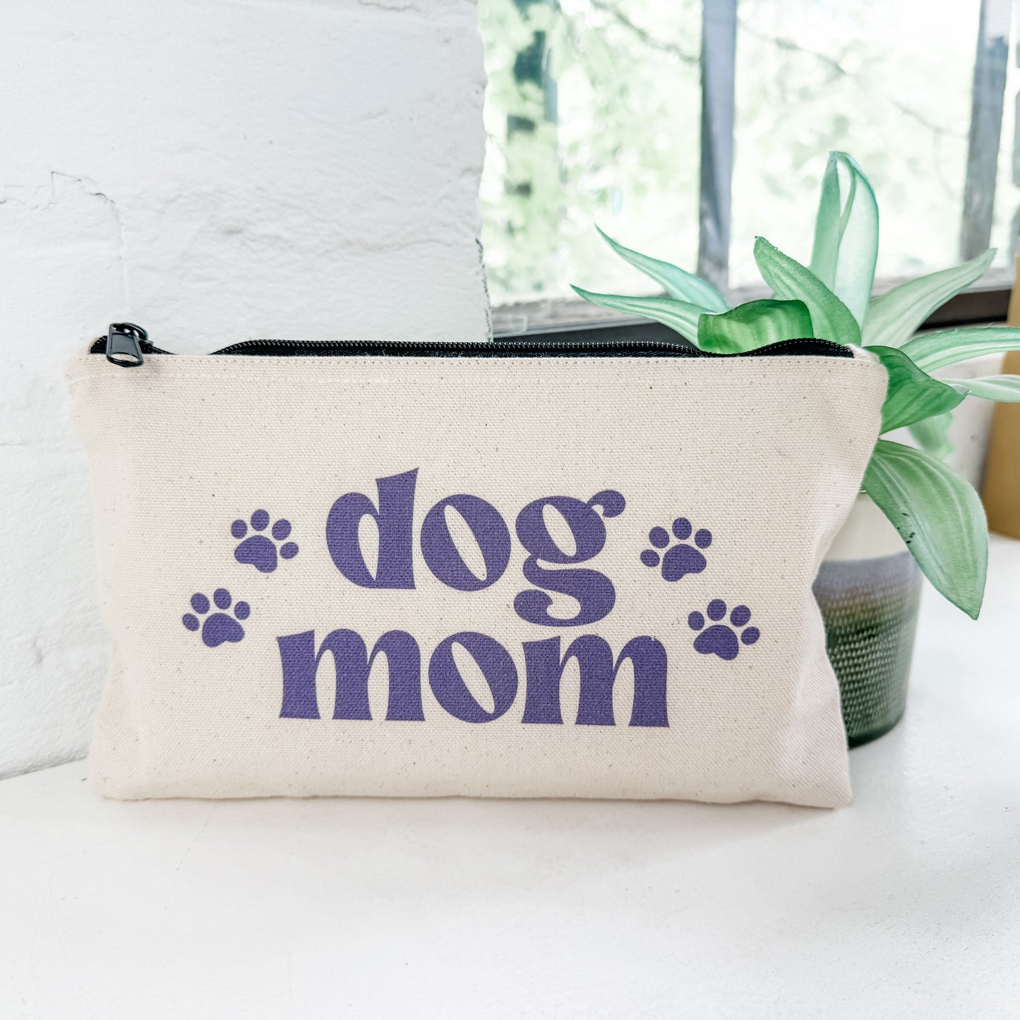 a dog mom pouch sitting on a table next to a plant