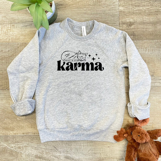 a gray sweatshirt with the word karna on it next to a teddy bear