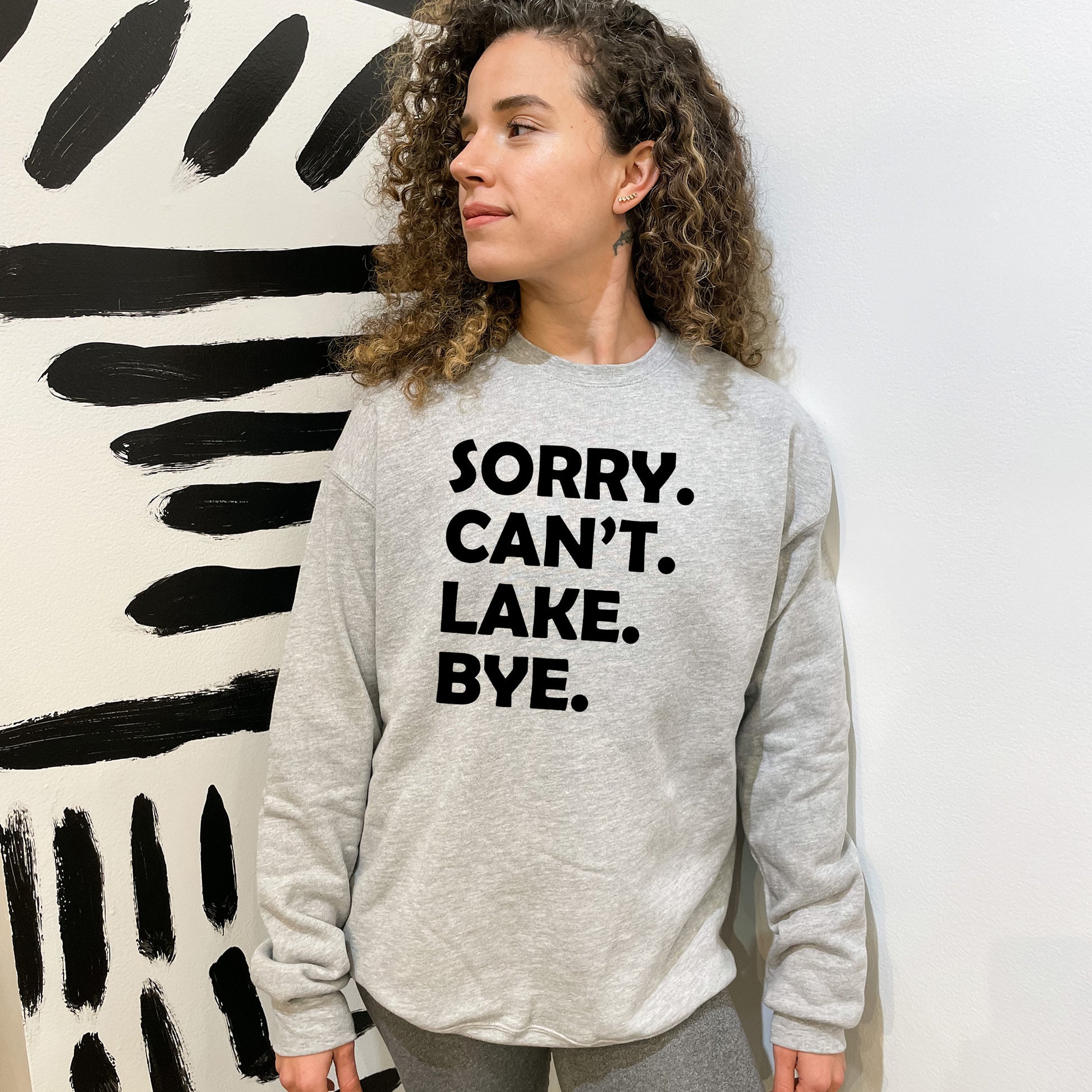 a woman standing in front of a painting wearing a sweatshirt that says sorry can '