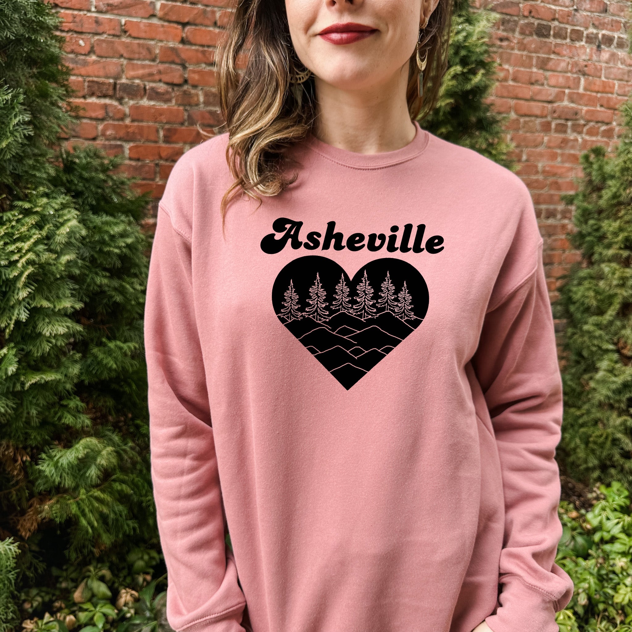 a woman wearing a pink sweatshirt with a heart and trees on it