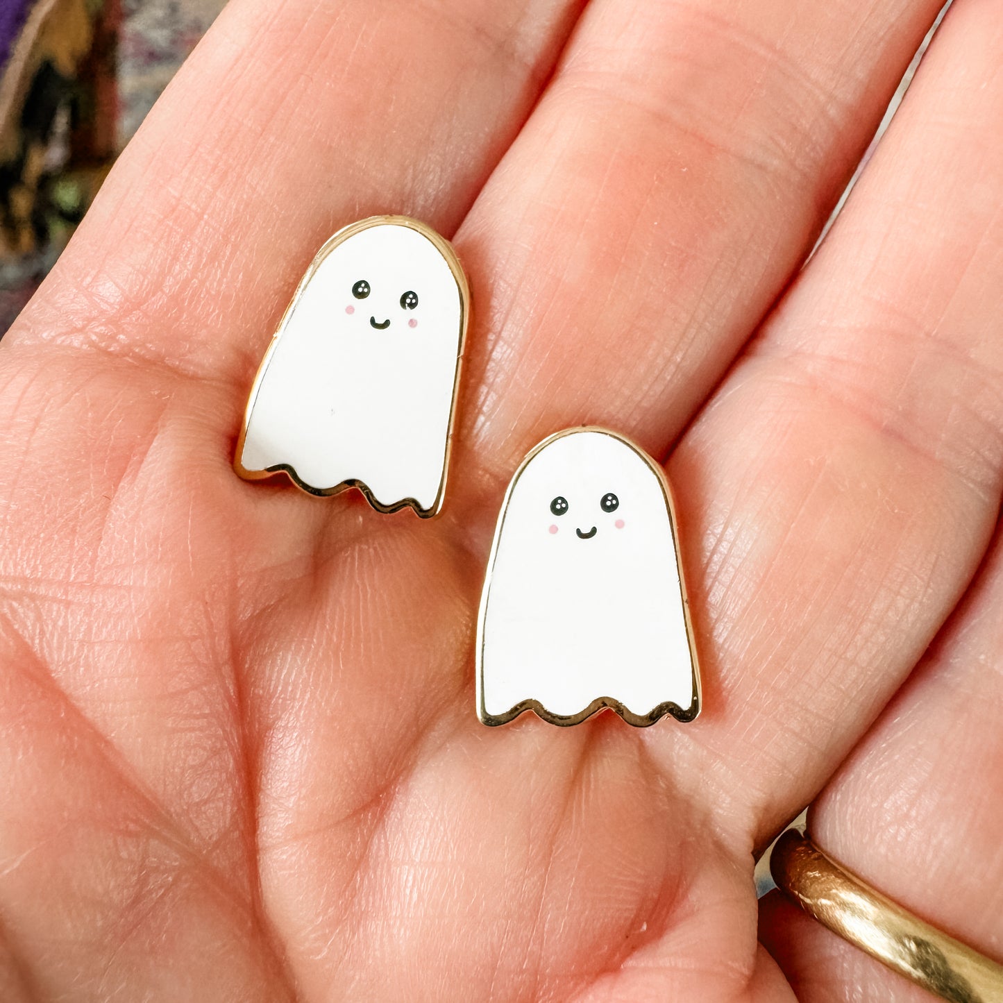 a pair of white ghost earrings sitting on a person's hand