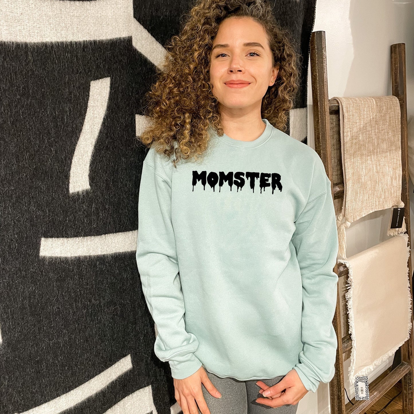 a woman standing next to a wall with a monster on it