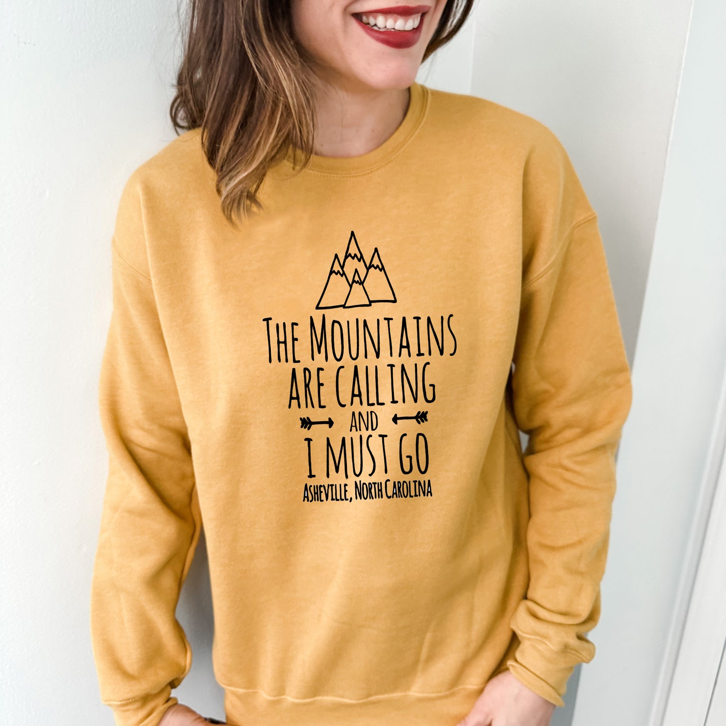 a woman wearing a sweatshirt that says the mountains are calling i must go