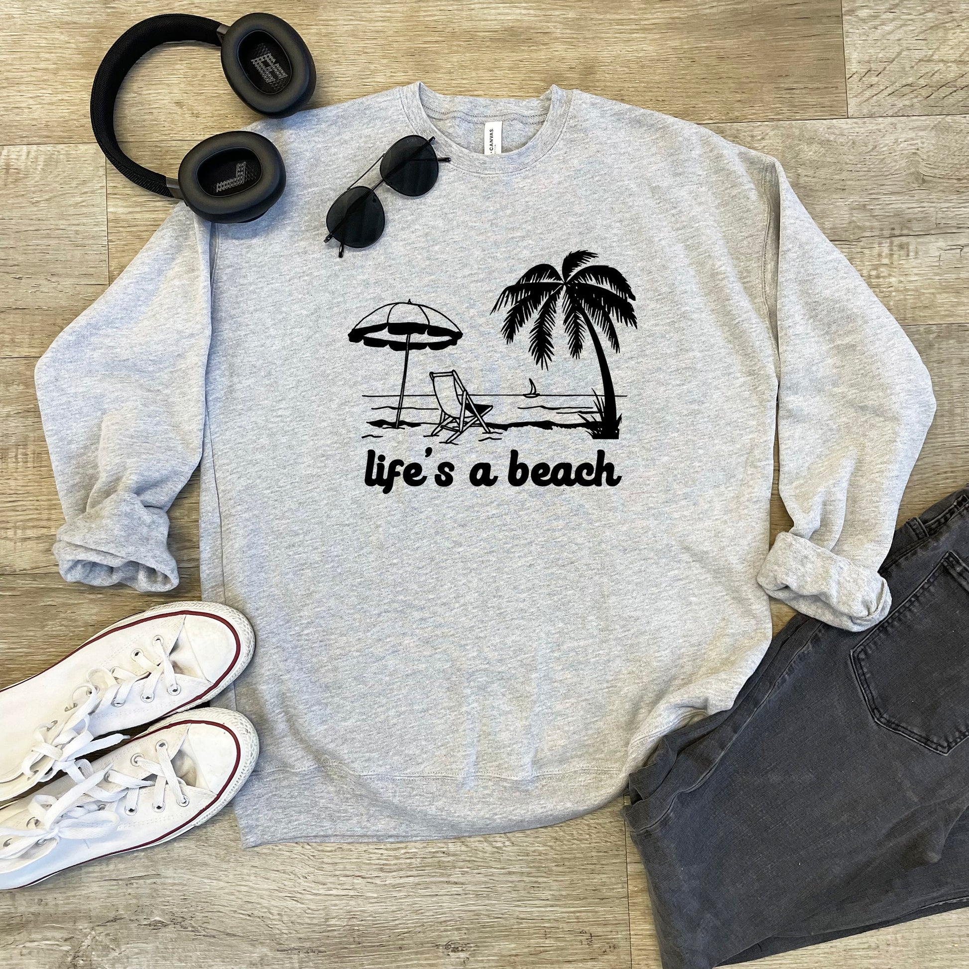 a sweatshirt that says life's a beach next to headphones and a pair