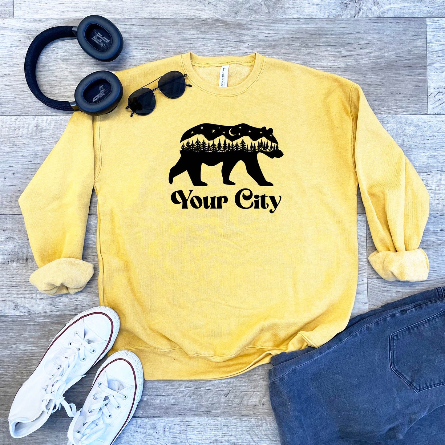 a yellow sweatshirt with a bear on it next to headphones and a pair of