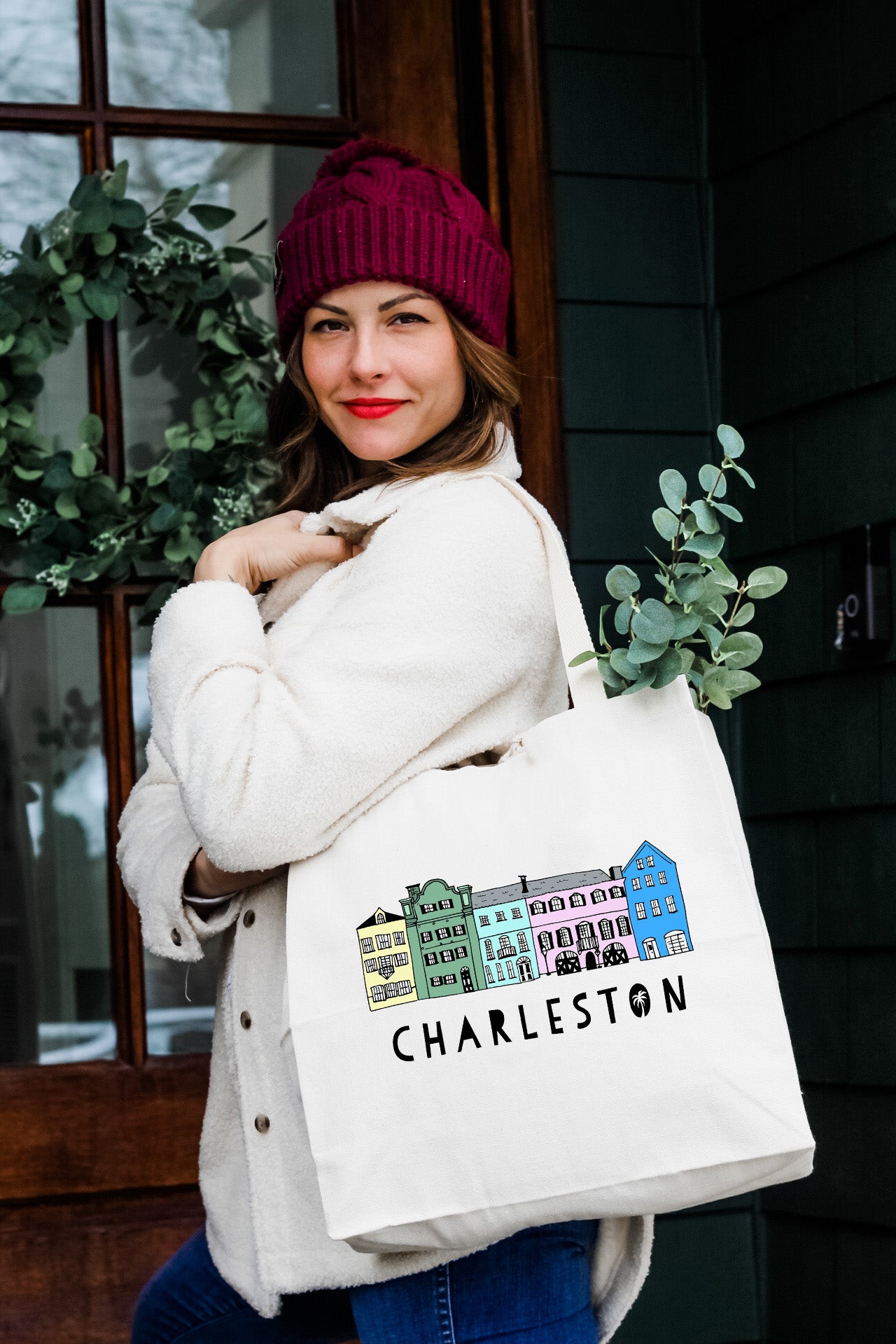 a woman carrying a white bag that says charleston