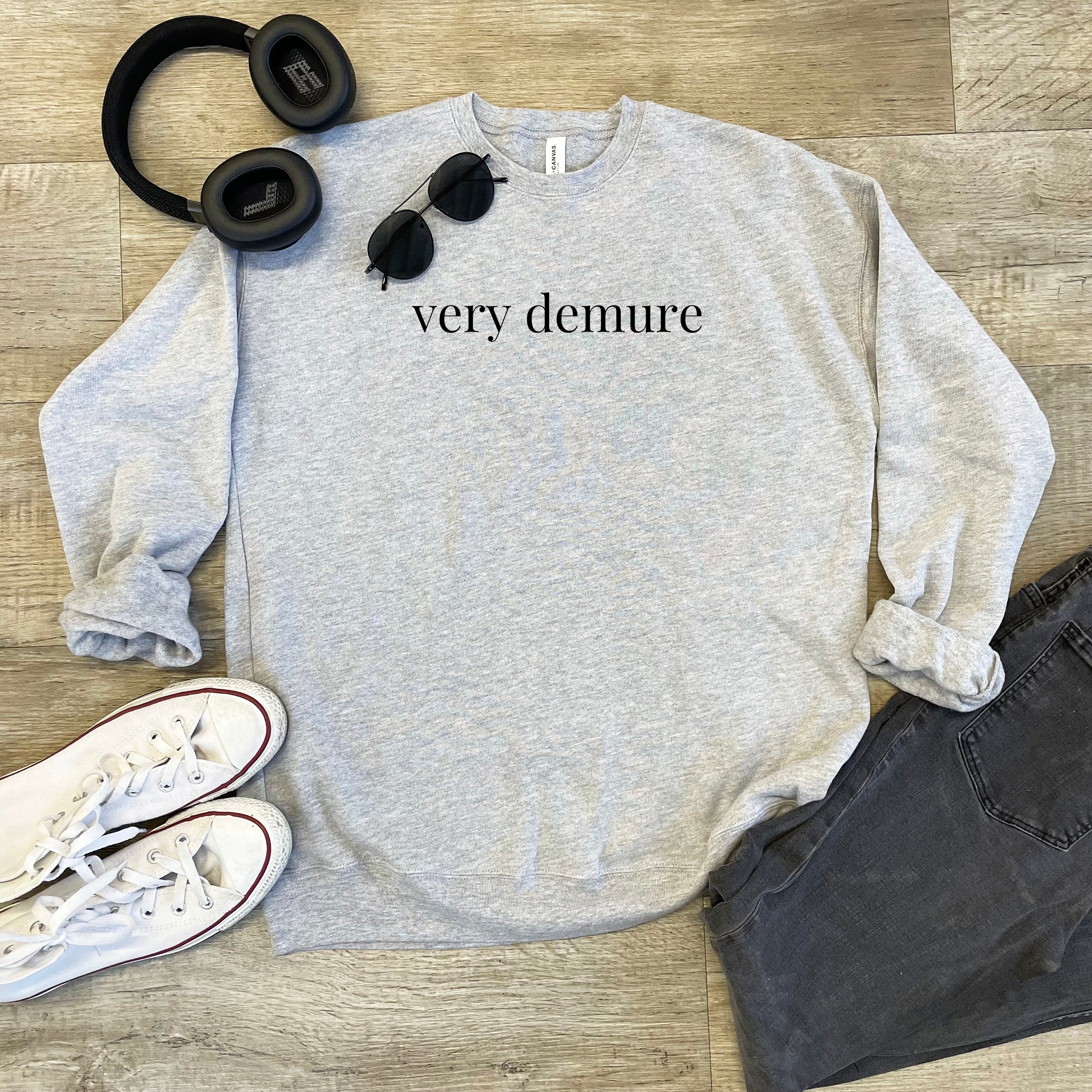 a sweatshirt that says very demure next to headphones