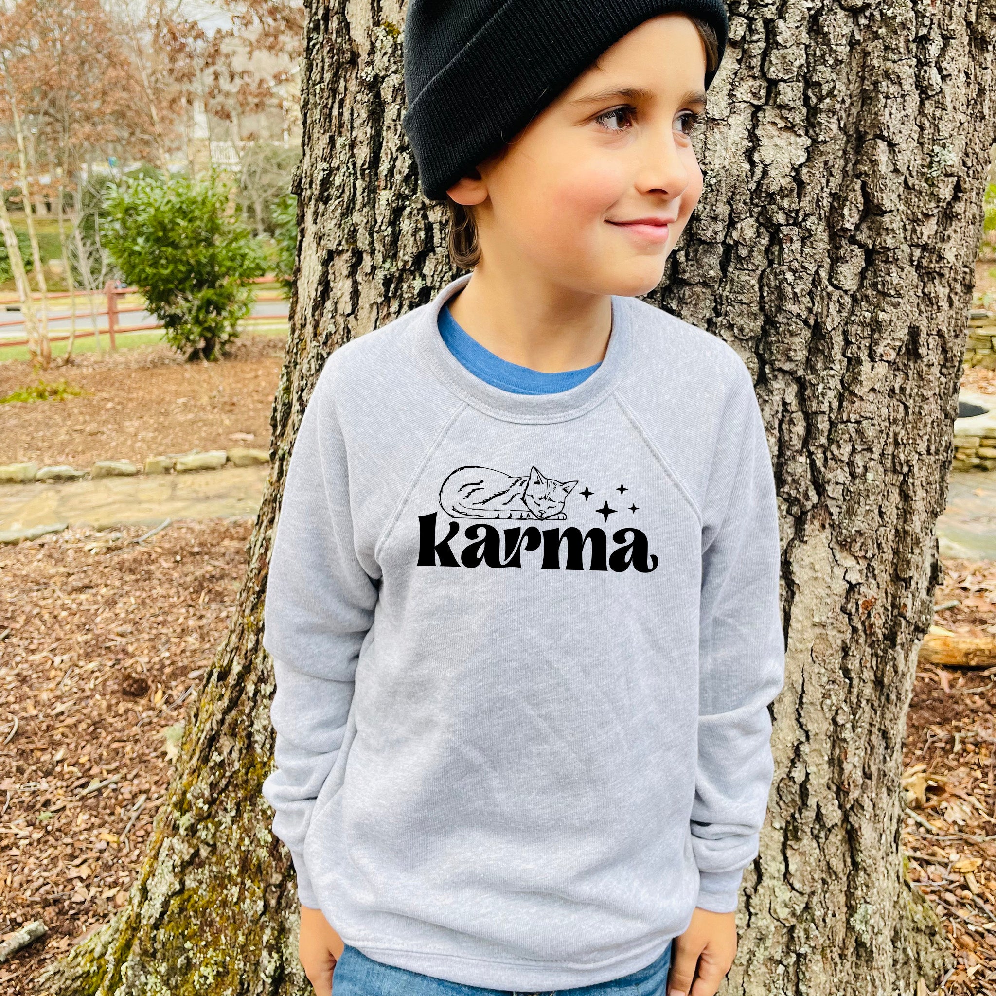 a young boy standing in front of a tree
