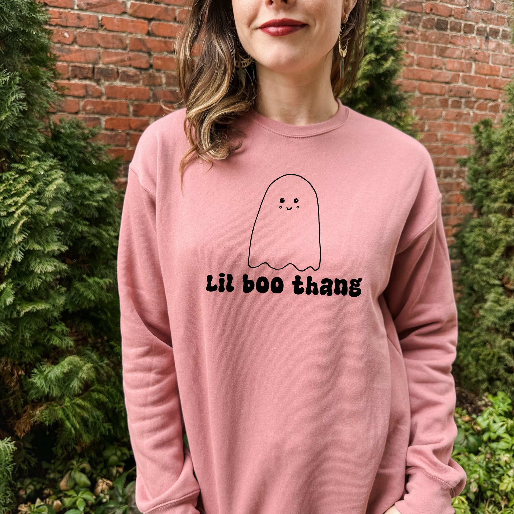 a woman wearing a pink sweatshirt with a ghost drawn on it