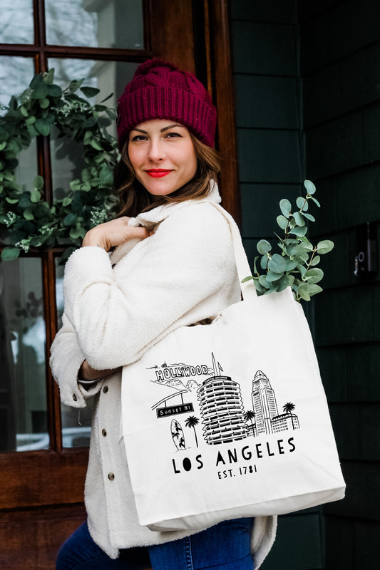 a woman carrying a white bag that says los angeles