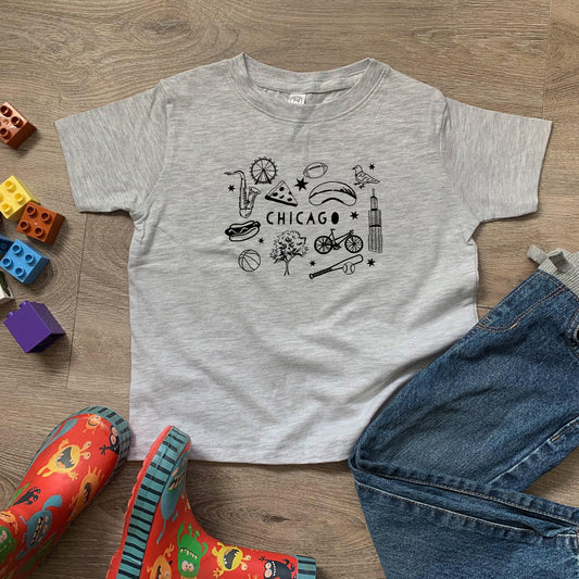 a child's chicago t - shirt and jeans on a wooden floor