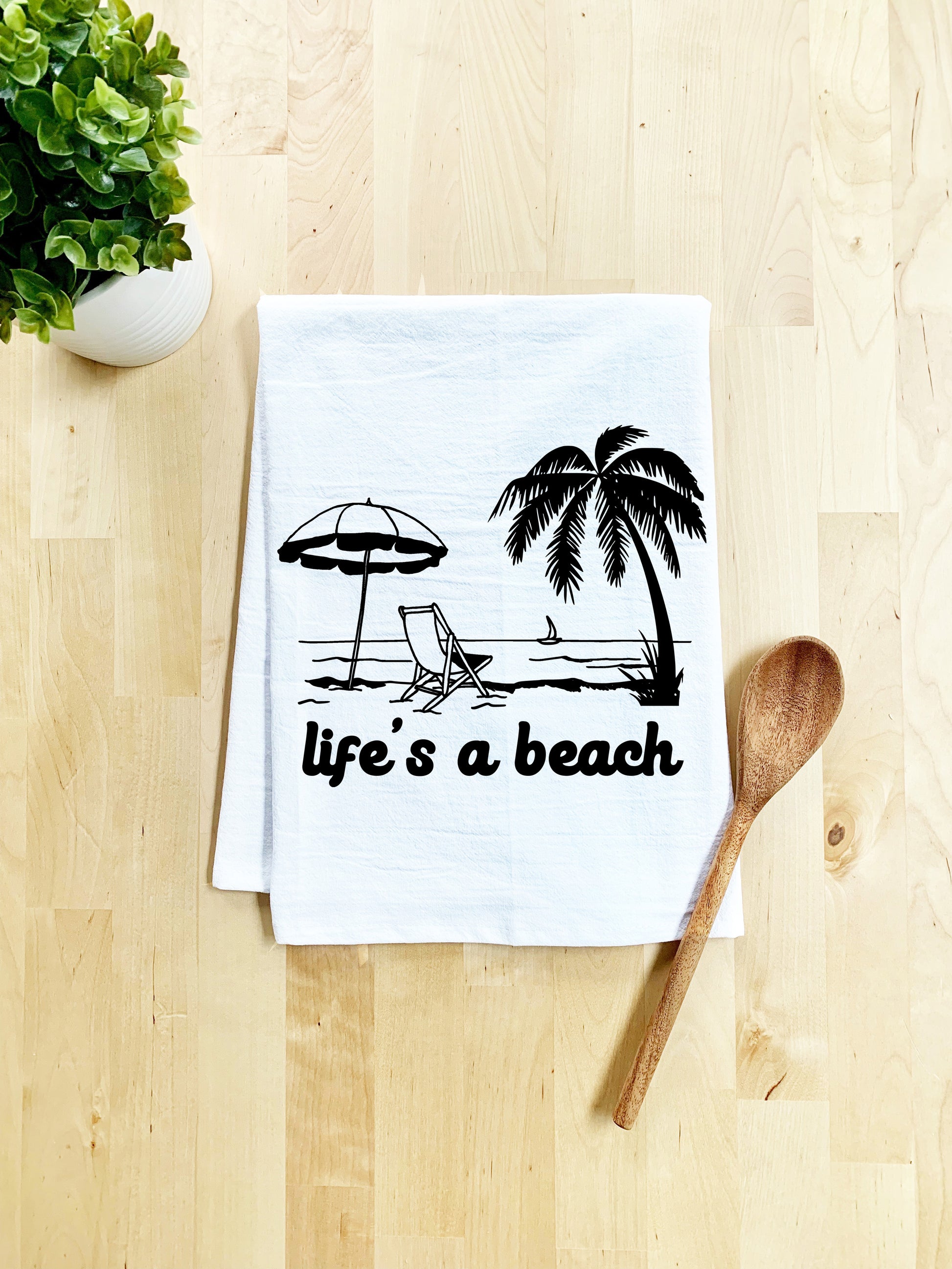 a tea towel that says life's a beach with a beach chair and umbrella