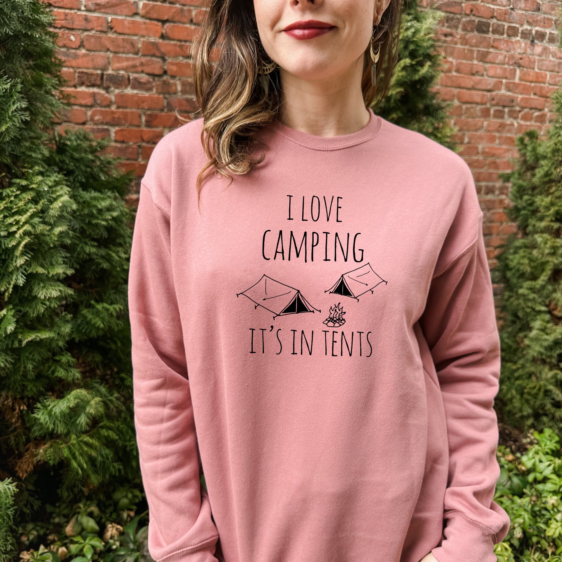 a woman wearing a pink sweatshirt that says i love camping it's in tents