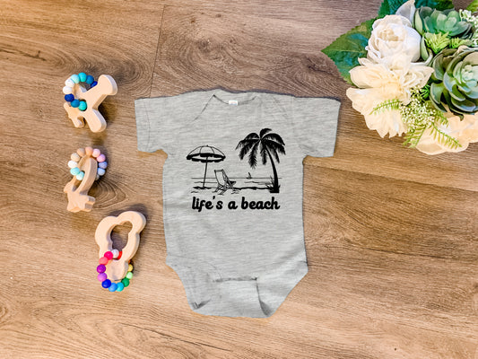 a baby bodysuit with a life's a beach design on it next to