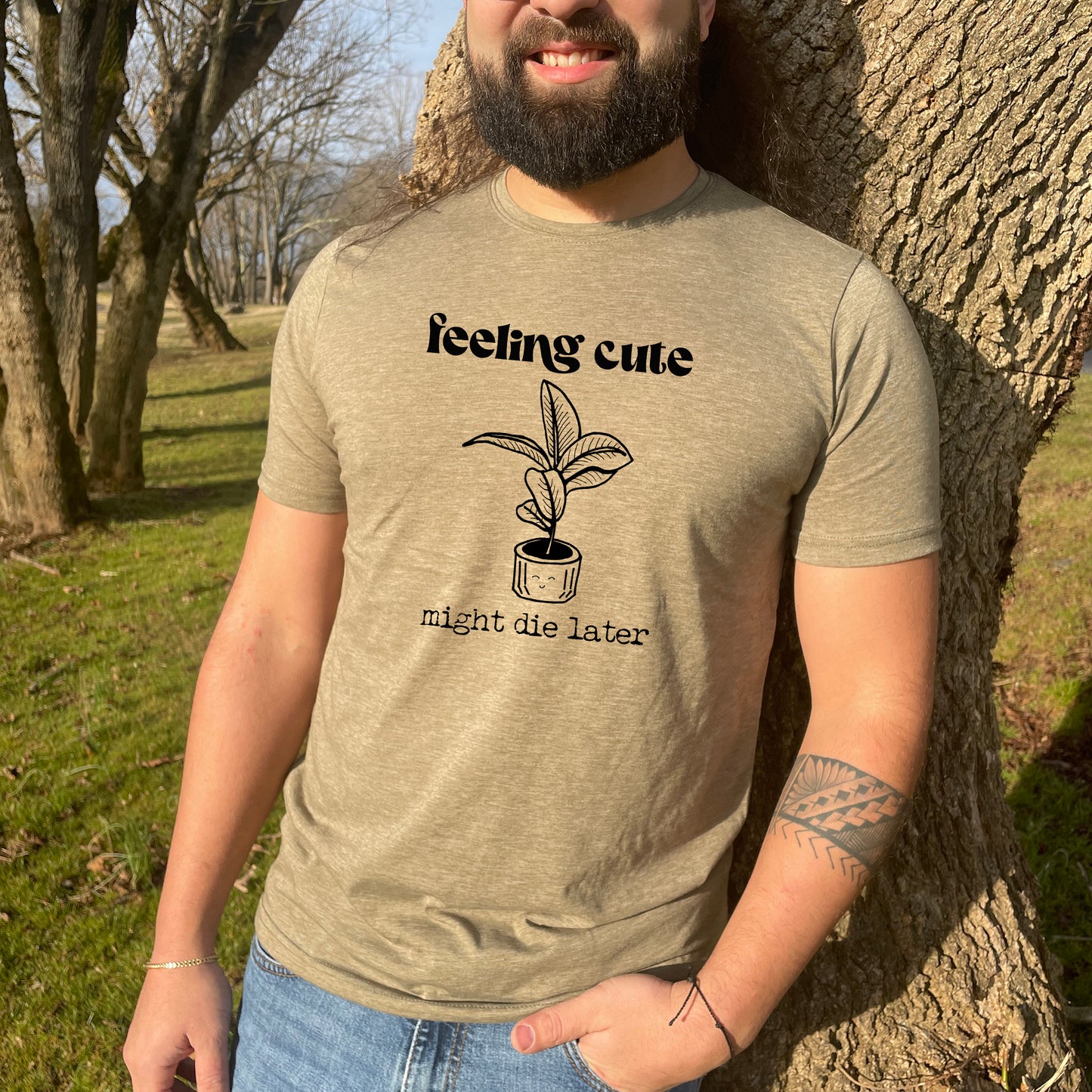 a man standing next to a tree wearing a t - shirt