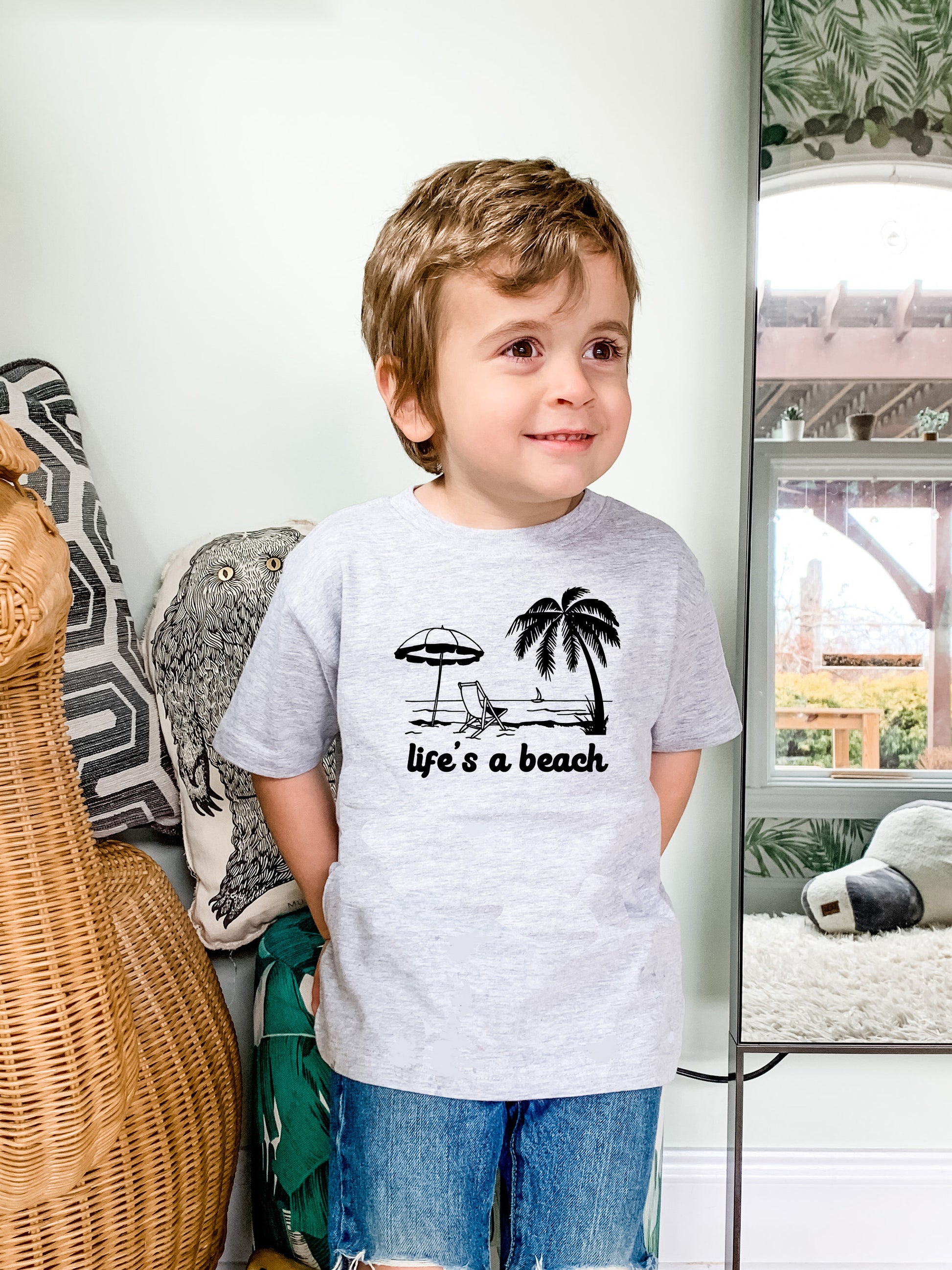 a young boy standing in front of a mirror wearing a life's a beach