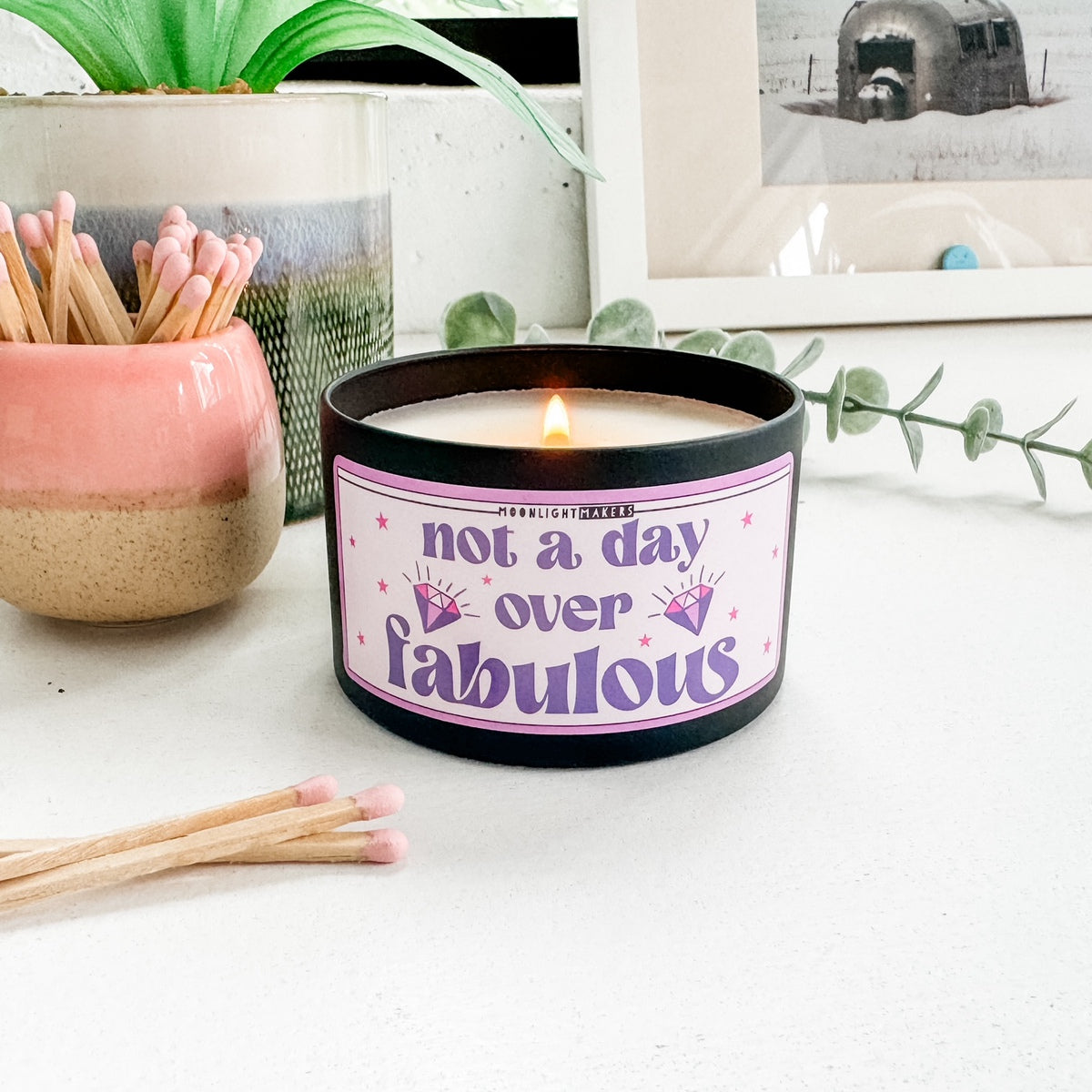 a candle sitting on top of a table next to a potted plant