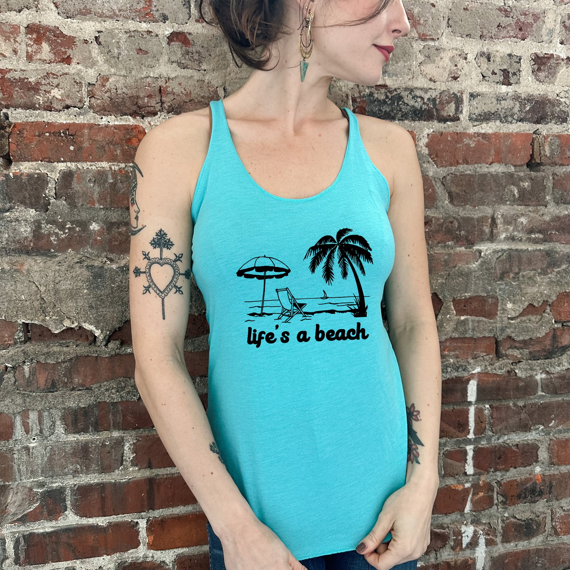 a woman wearing a blue tank top with a palm tree and a life's