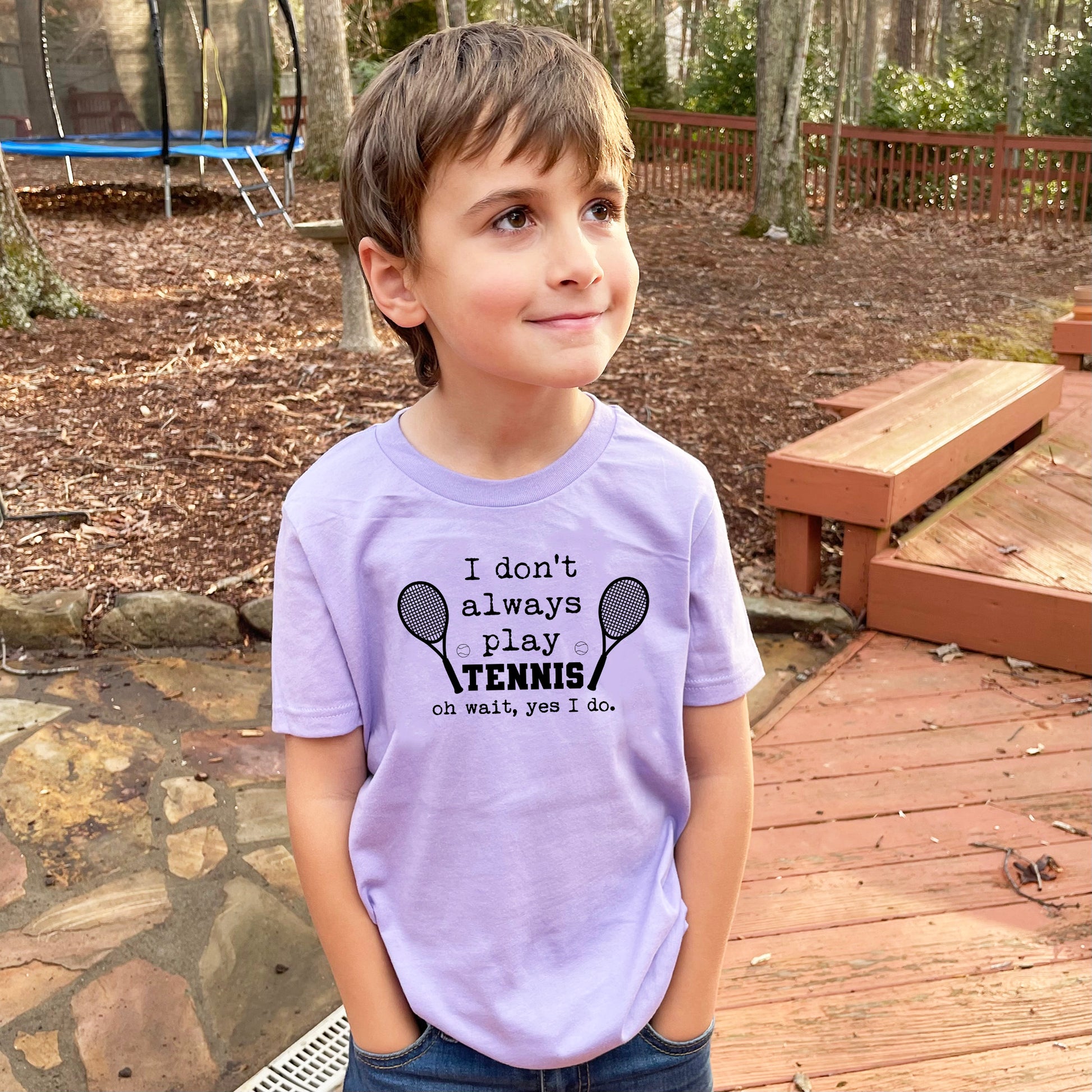 a young boy standing on a deck wearing a purple shirt