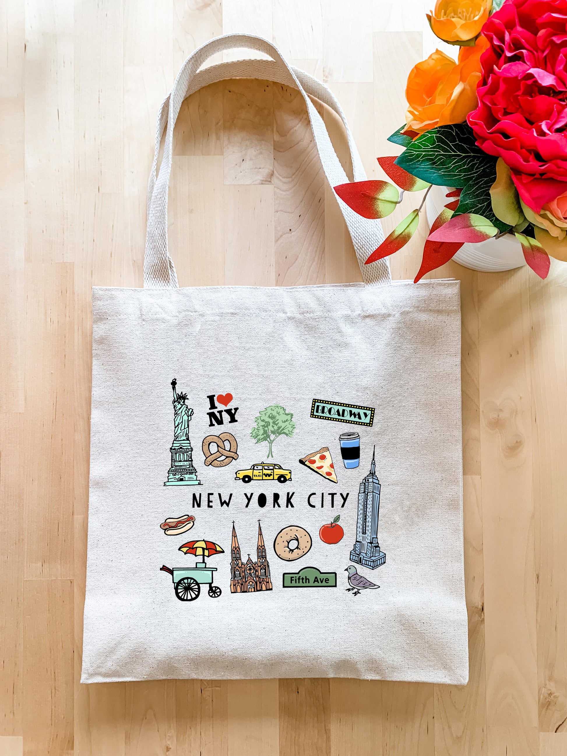 a new york city tote bag next to a bouquet of flowers